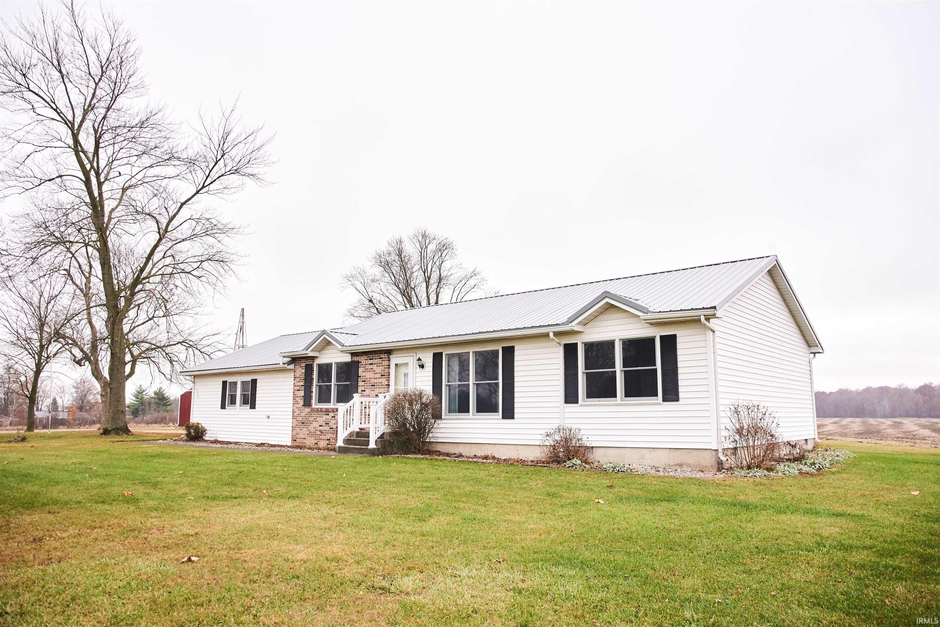 Ranch-style home featuring a front yard, a metal roof, and brick siding