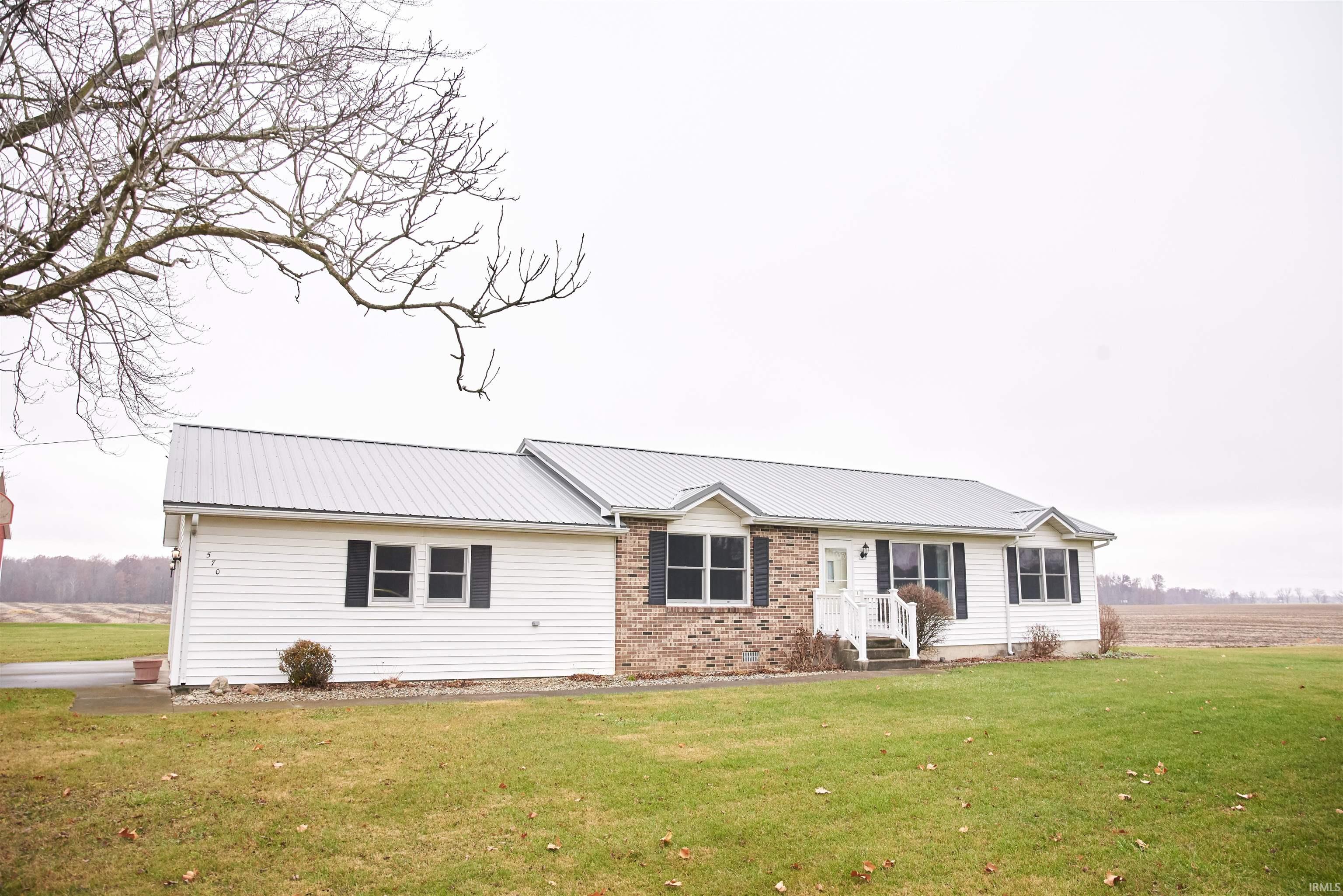 Ranch-style house featuring a front lawn, a metal roof, and brick siding