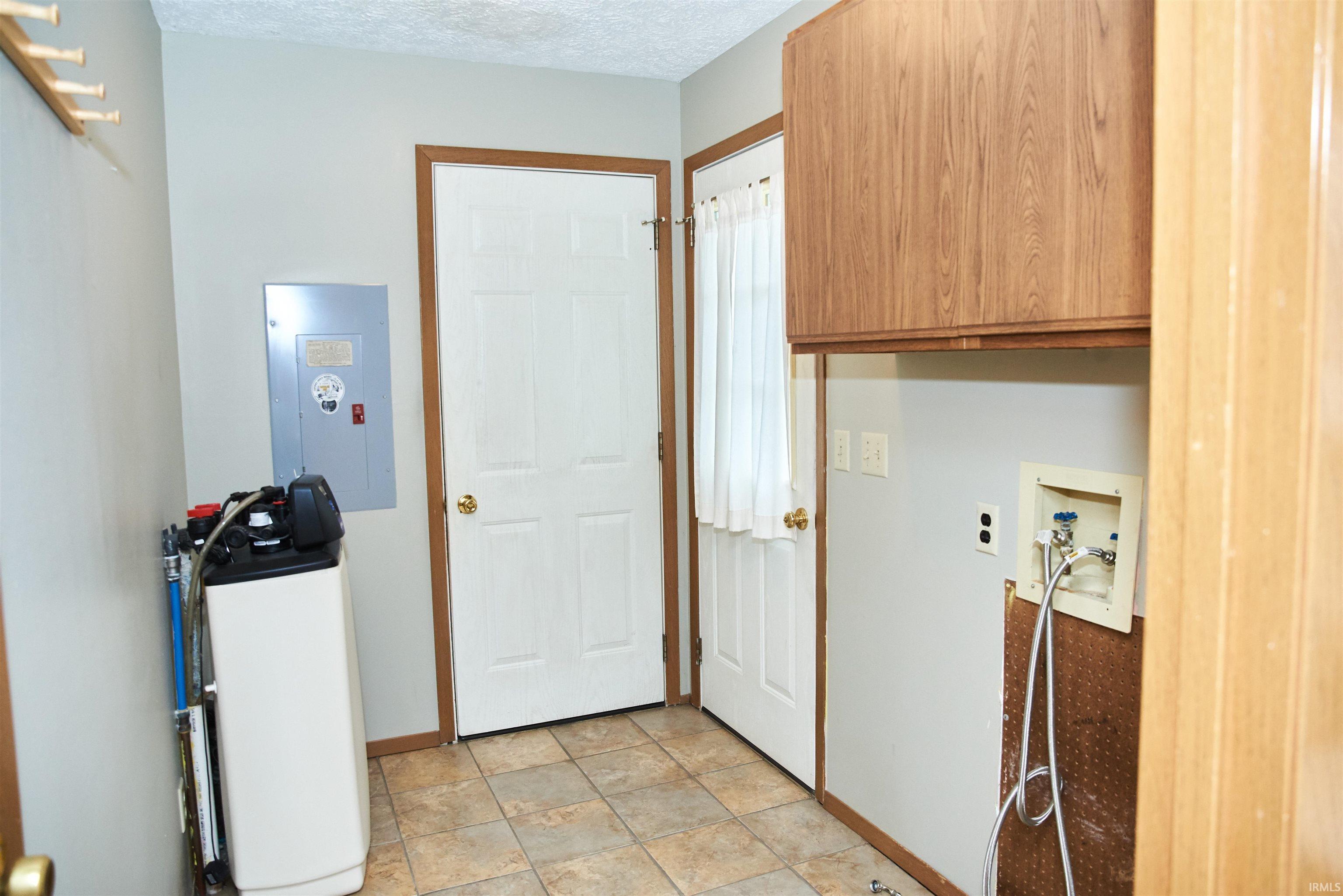 Laundry room with electric panel, hookup for a washing machine, a textured ceiling, and cabinet space