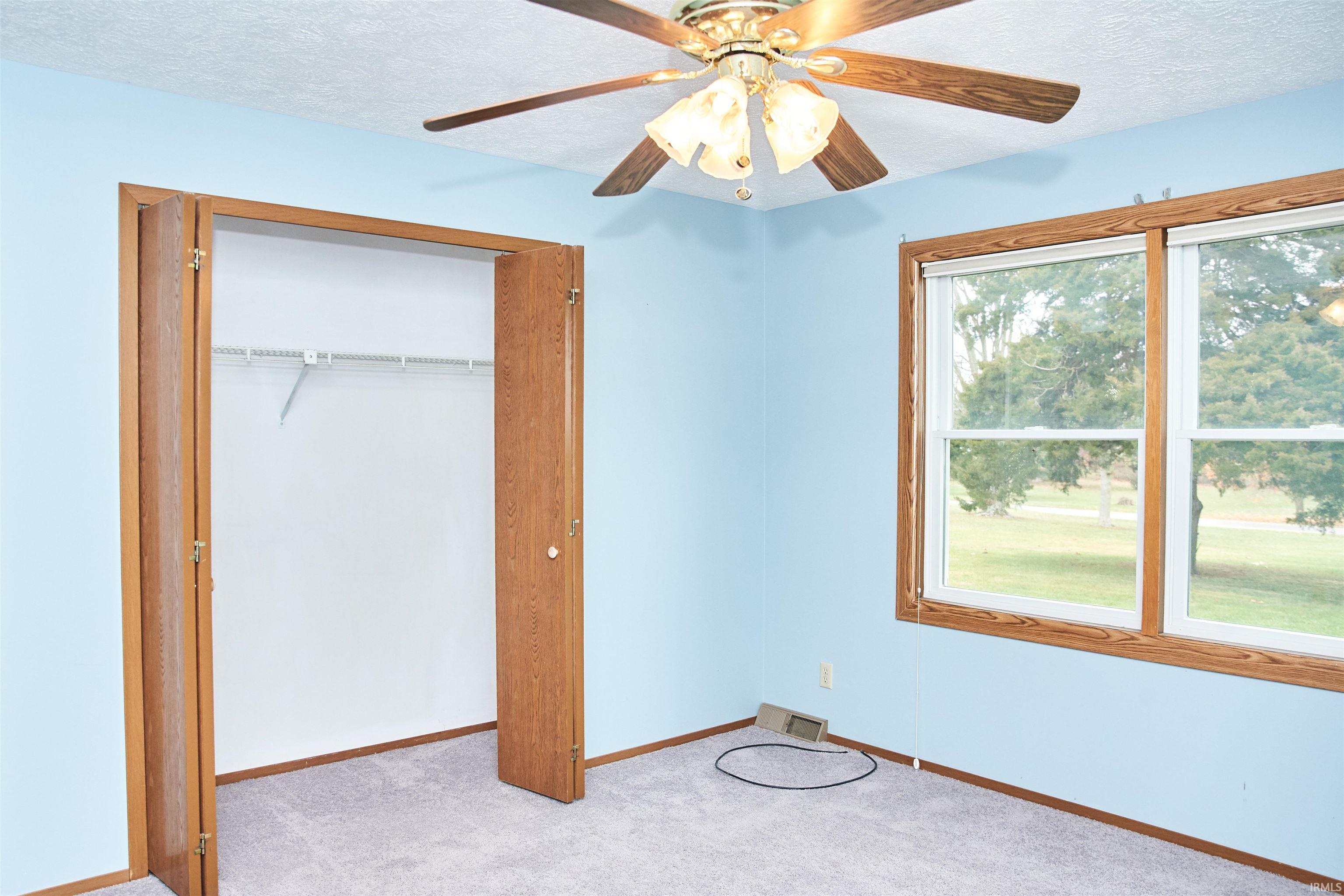 Unfurnished bedroom with a textured ceiling, a closet, carpet, and ceiling fan