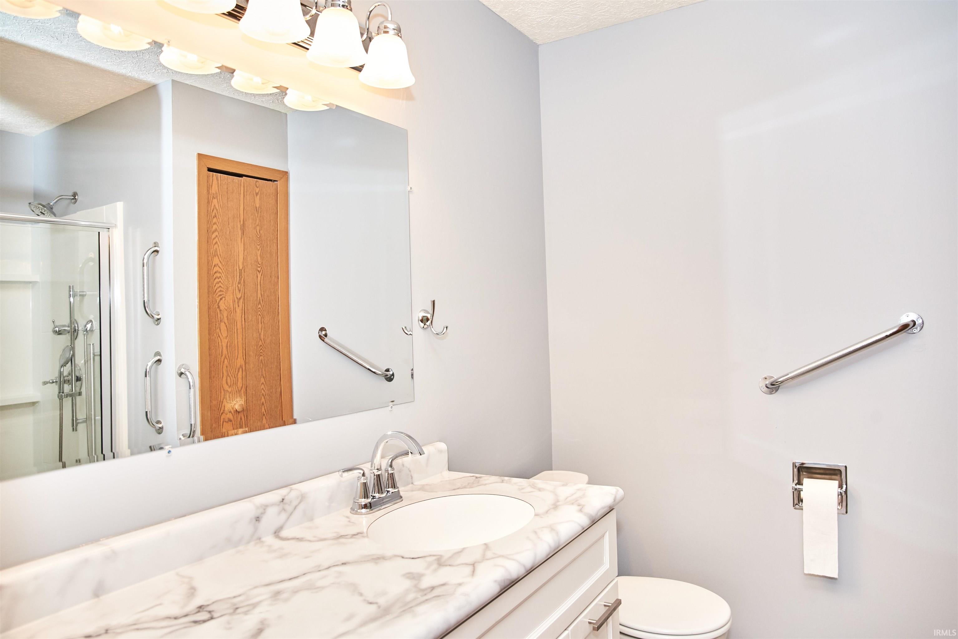 Bathroom featuring vanity, a stall shower, and a textured ceiling
