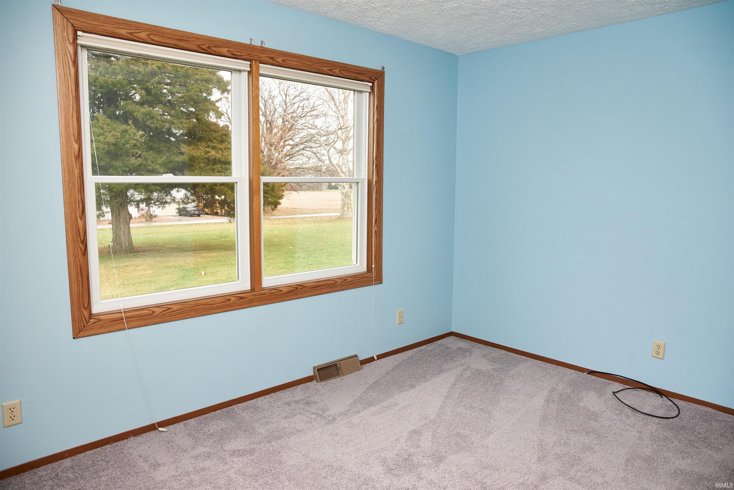 Carpeted empty room with baseboards and a textured ceiling