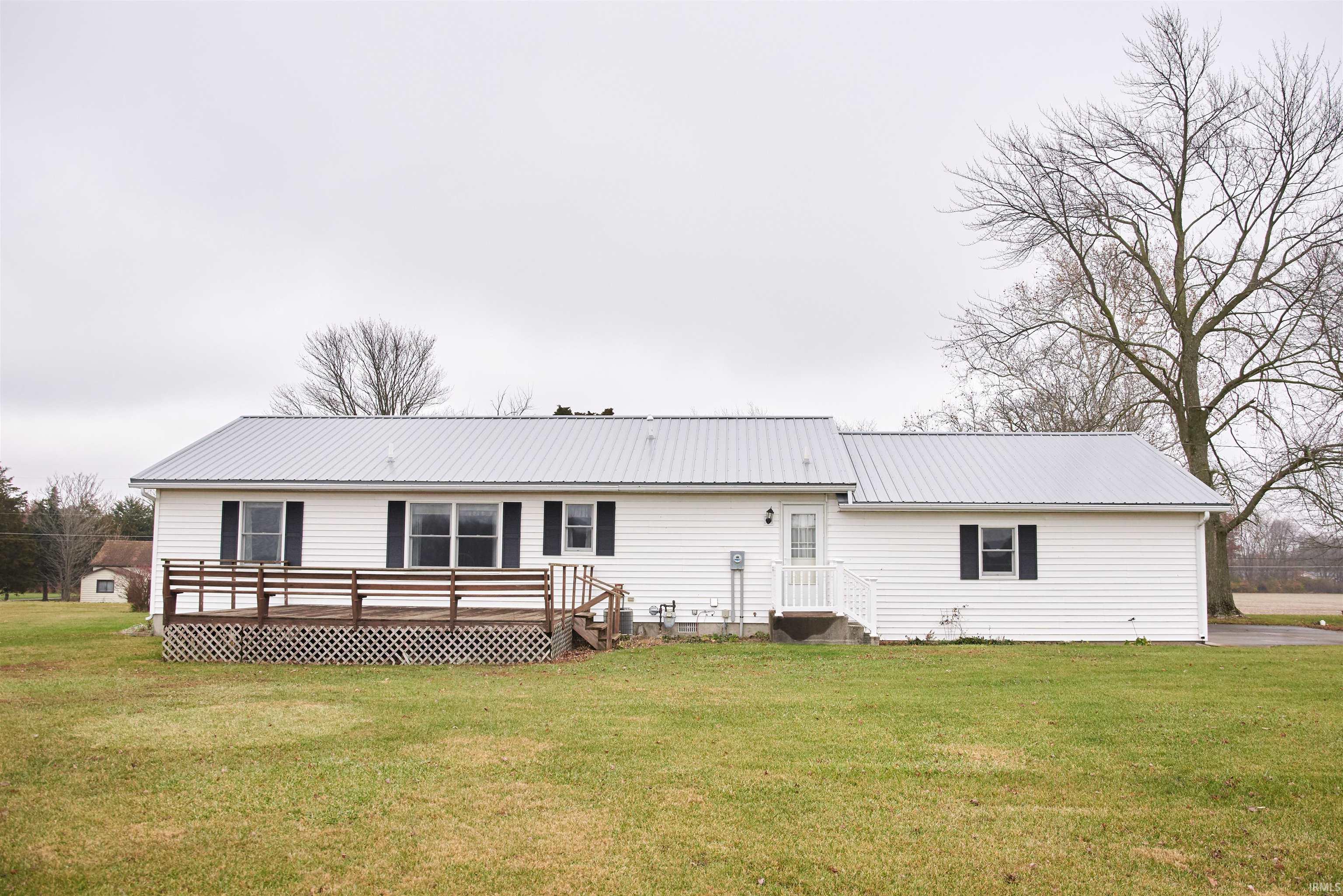 Back of house featuring a yard, a metal roof, and a wooden deck