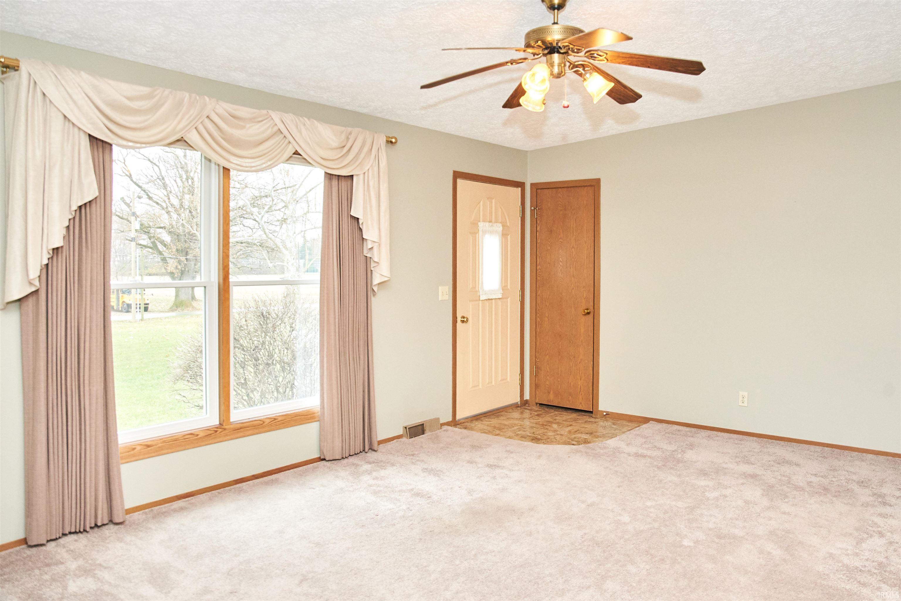 Empty room with a textured ceiling, light colored carpet, and a ceiling fan