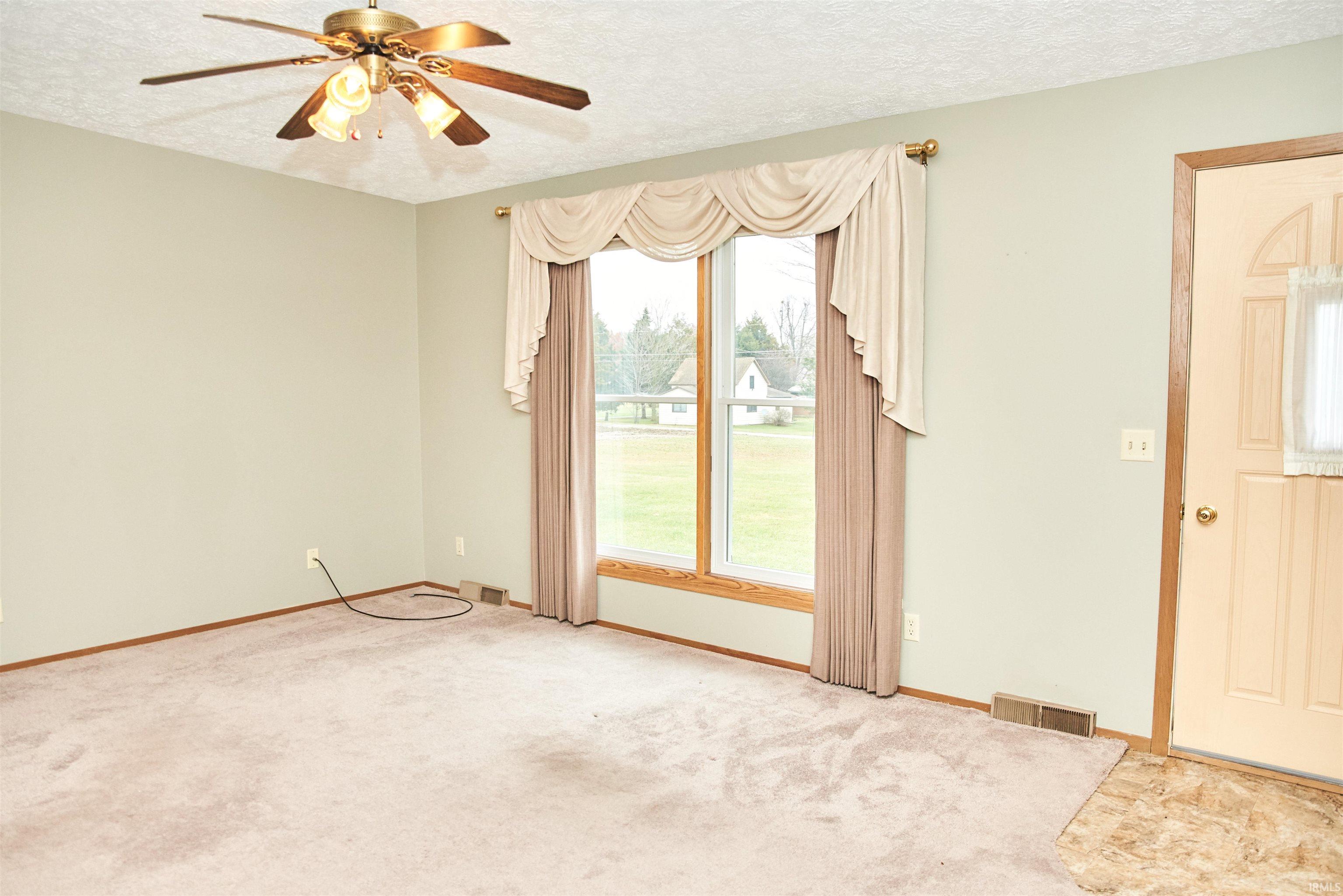 Spare room with a textured ceiling, a ceiling fan, and light colored carpet