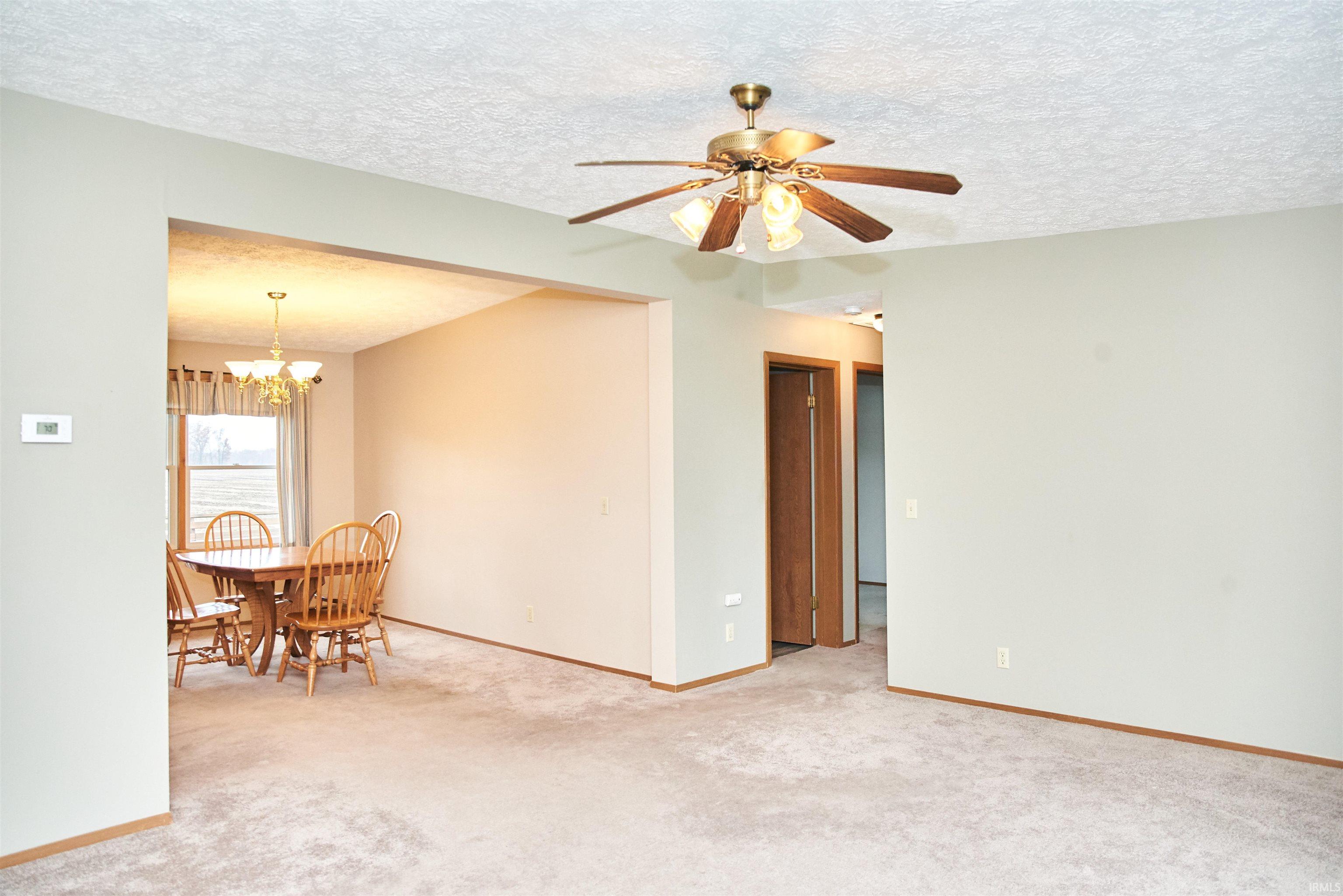 Dining space featuring a textured ceiling, light carpet, a chandelier, and a ceiling fan