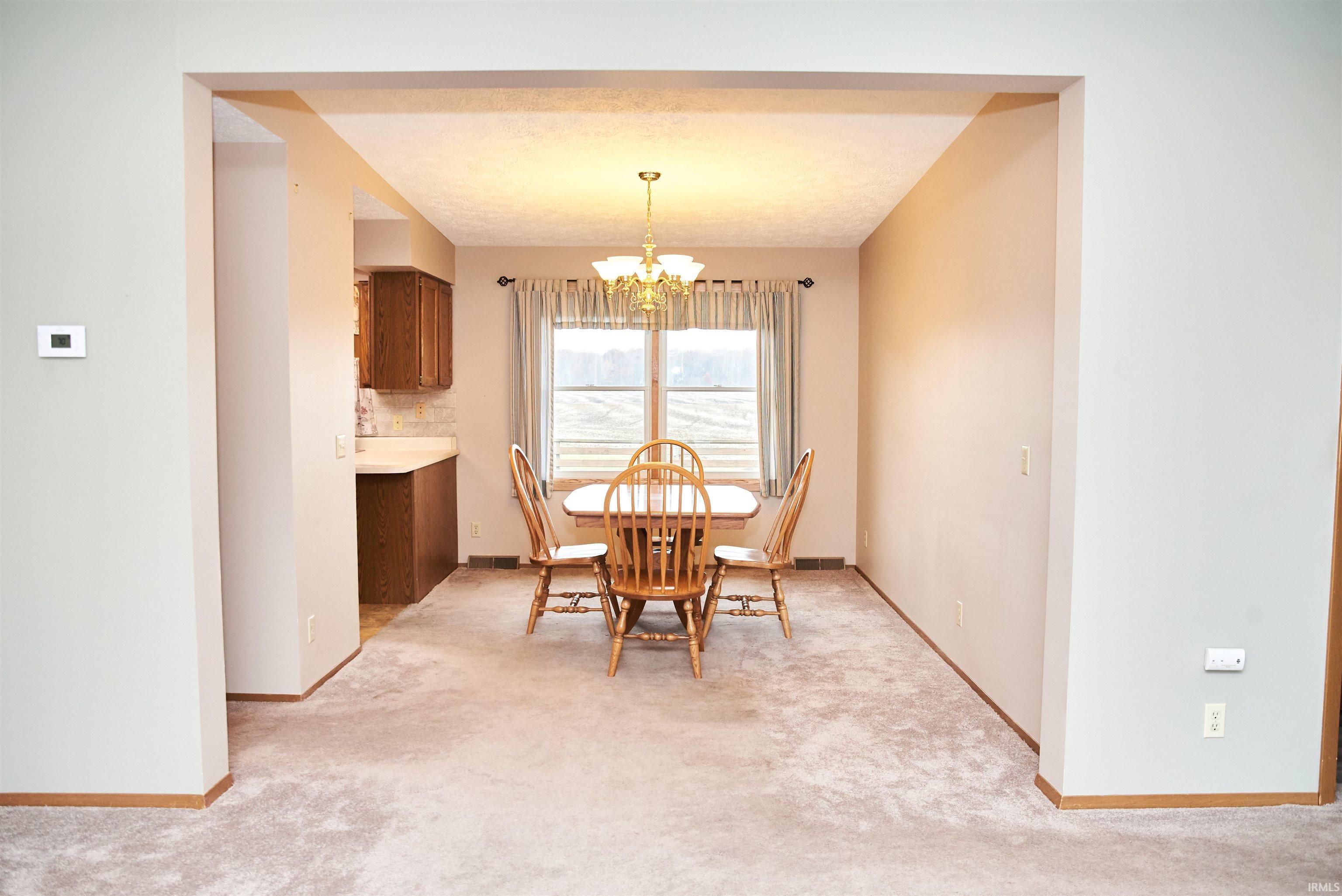 Dining area with a chandelier and light carpet