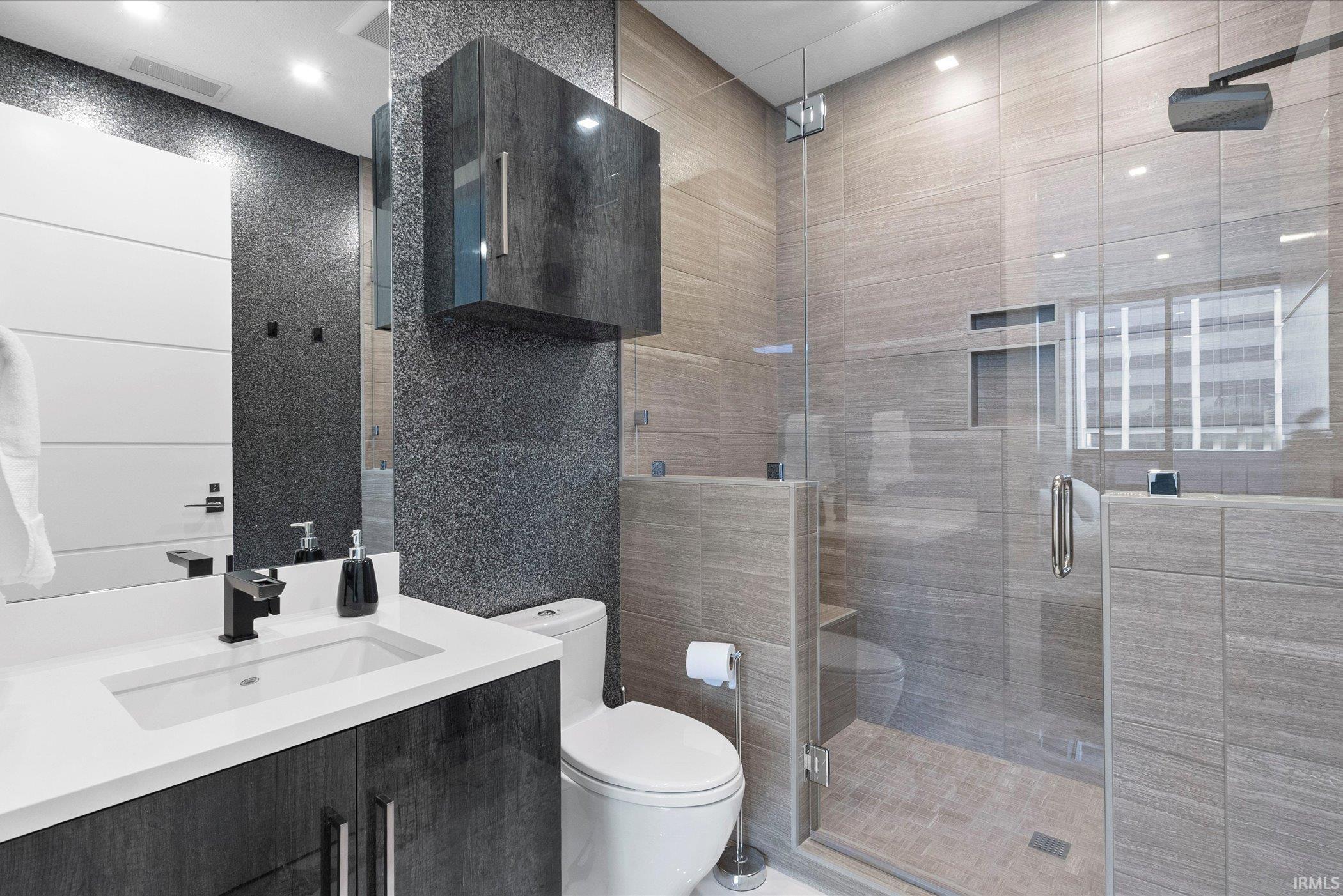 Bathroom with vanity, tile walls, and a stall shower