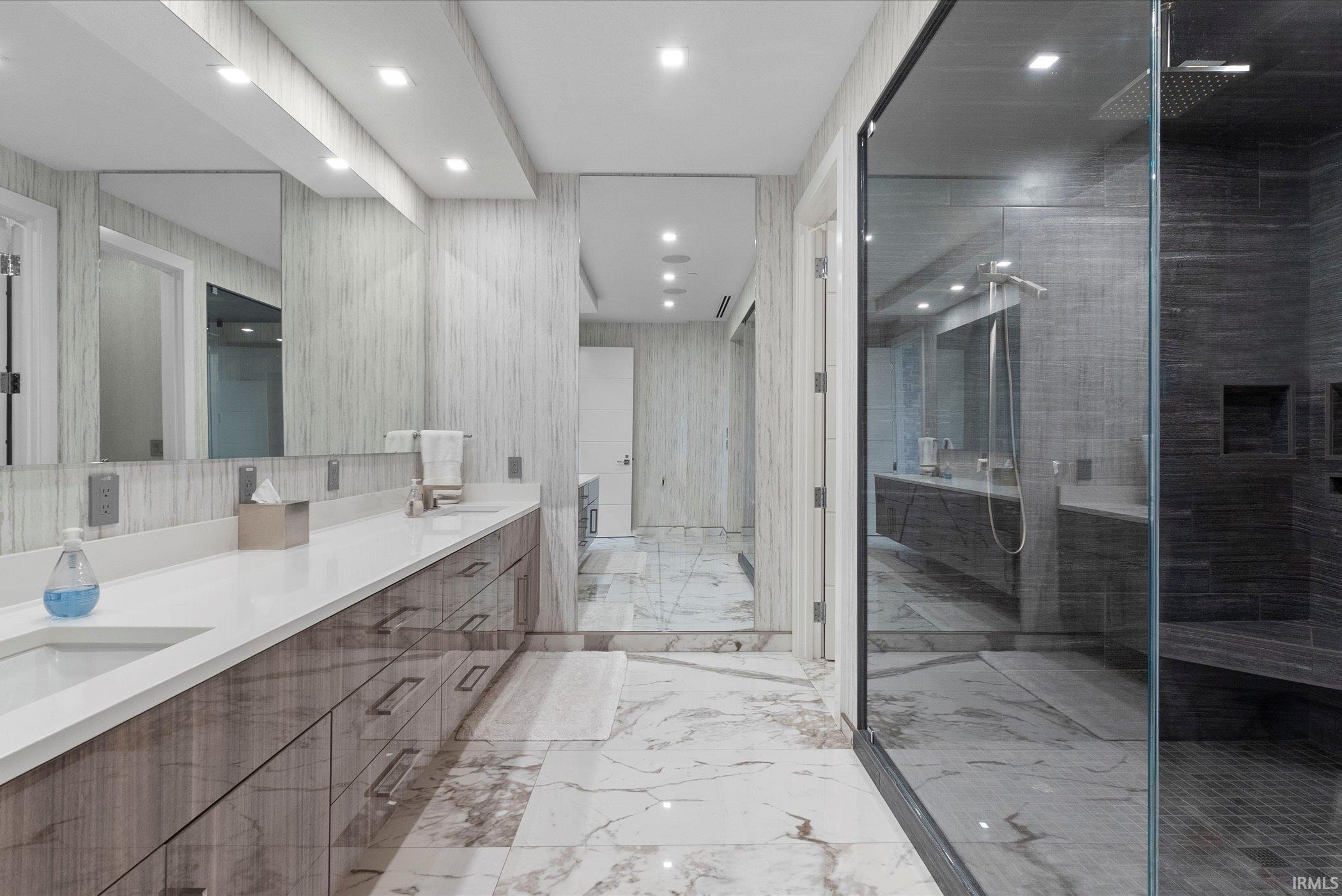 Bathroom with double vanity, an enclosed shower, light marble finish floors, and recessed lighting