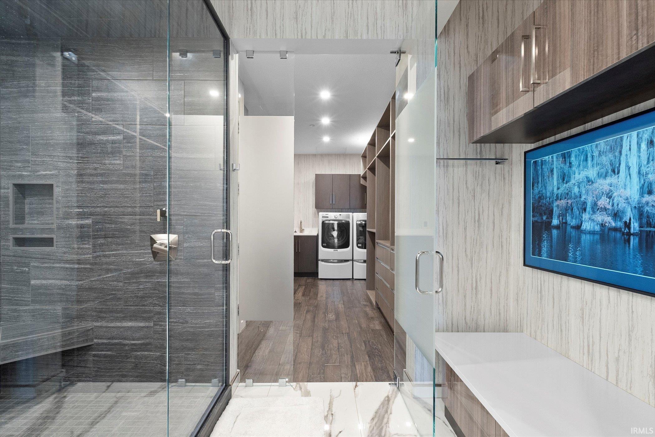 Full bath with a shower stall, vanity, washing machine and dryer, and recessed lighting