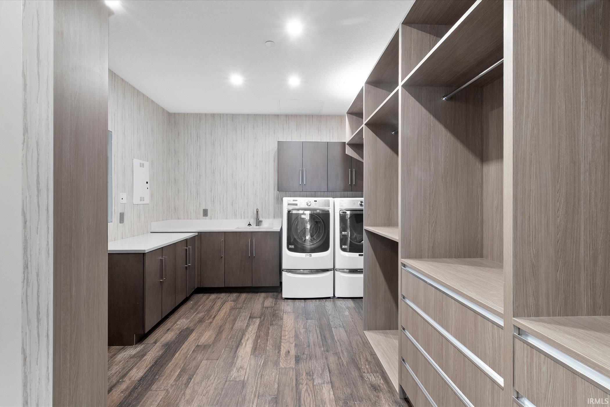 Laundry area with dark wood-type flooring, cabinet space, washer and clothes dryer, and recessed lighting