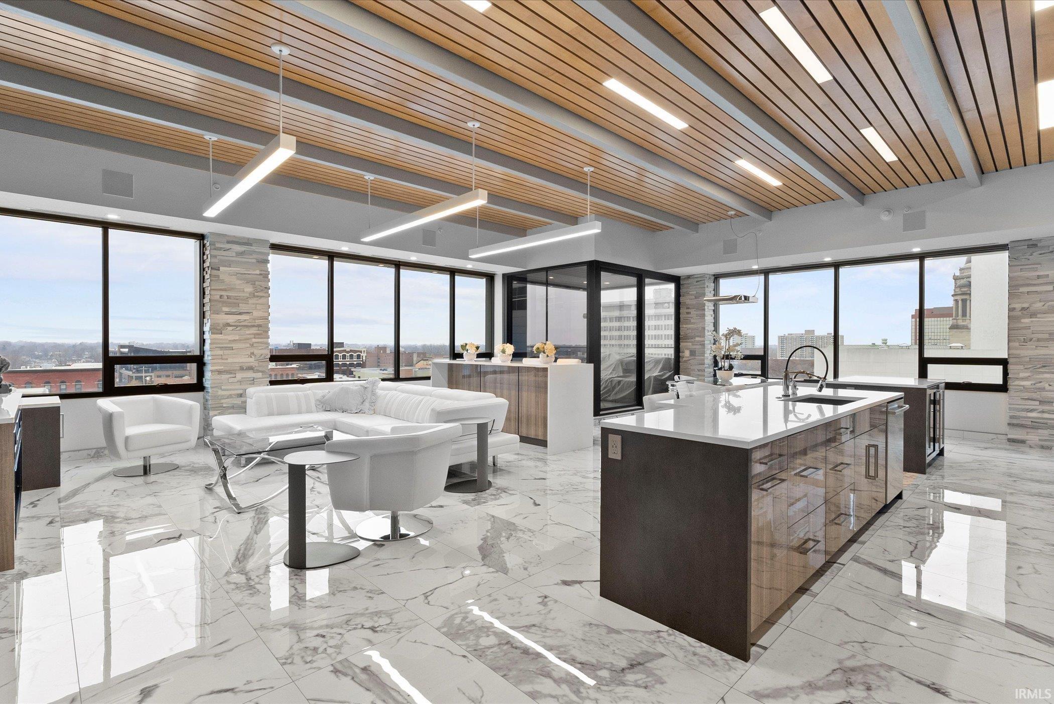 Kitchen featuring open floor plan, light stone counters, dark brown cabinets, modern cabinets, and beamed ceiling