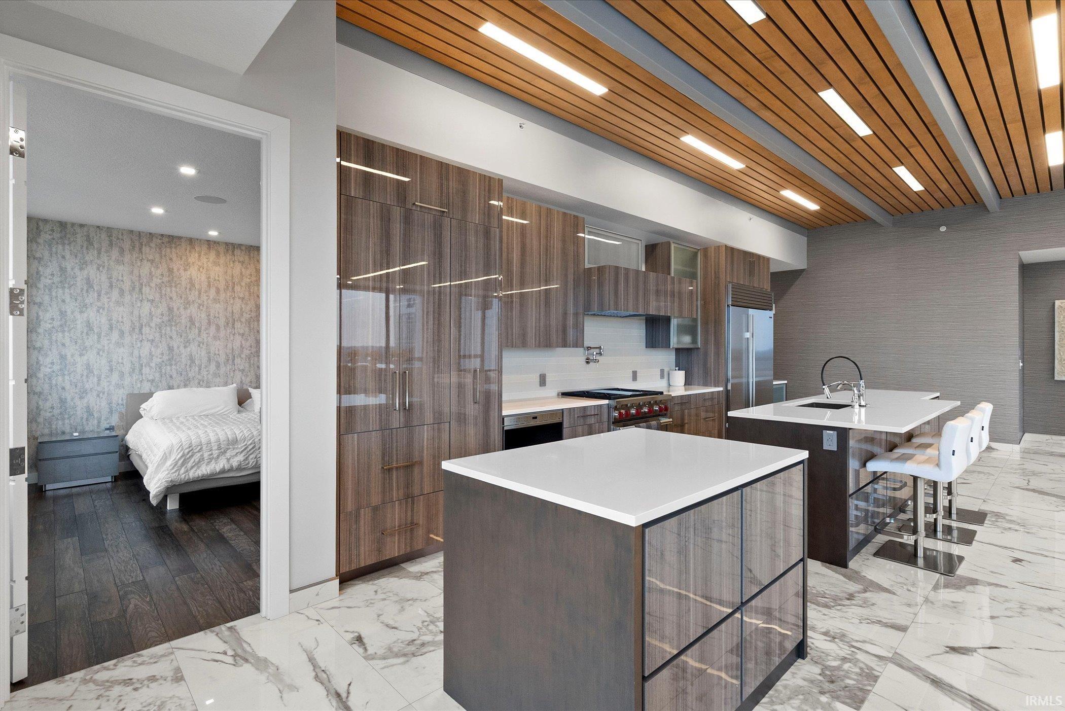 Kitchen with a kitchen island with sink, modern cabinets, a breakfast bar area, and light marble finish floors