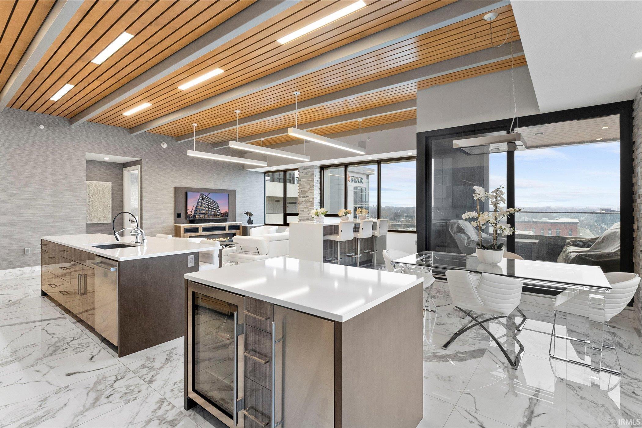 Kitchen featuring an island with sink, modern cabinets, light marble finish floors, wine cooler, and wooden ceiling