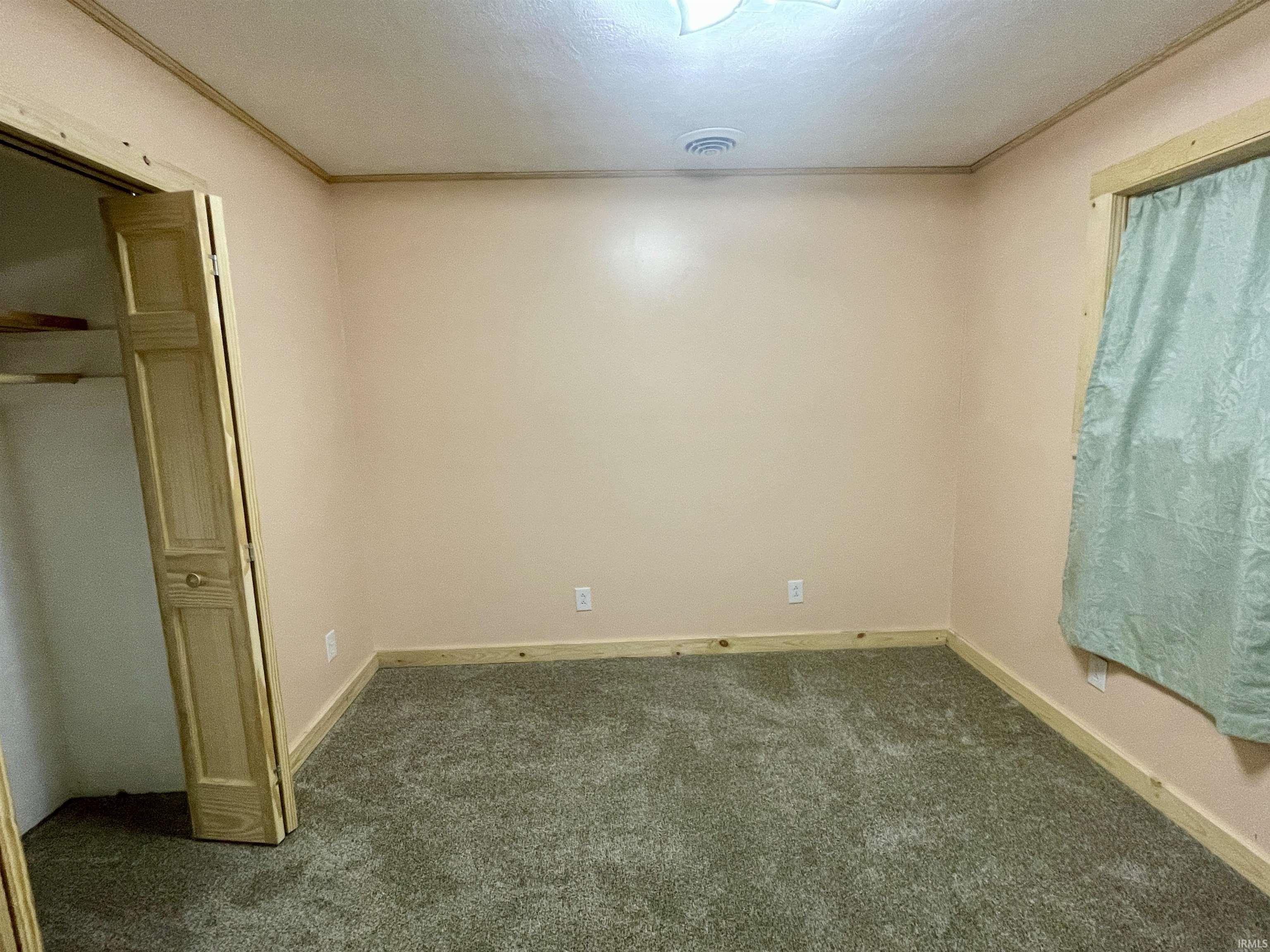 Unfurnished bedroom featuring dark colored carpet, crown molding, a closet, and a textured ceiling