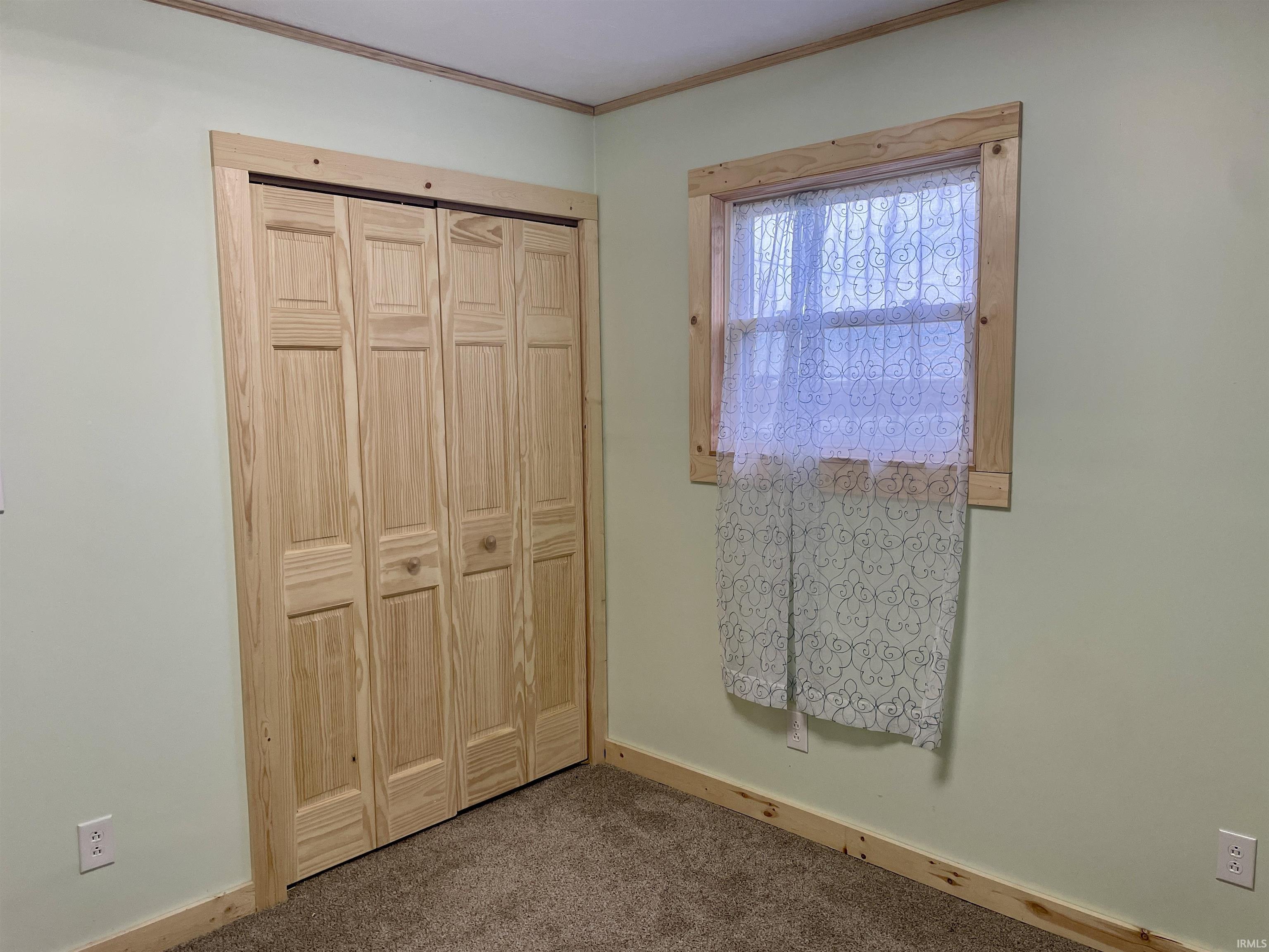 Unfurnished bedroom with a closet, carpet flooring, and crown molding