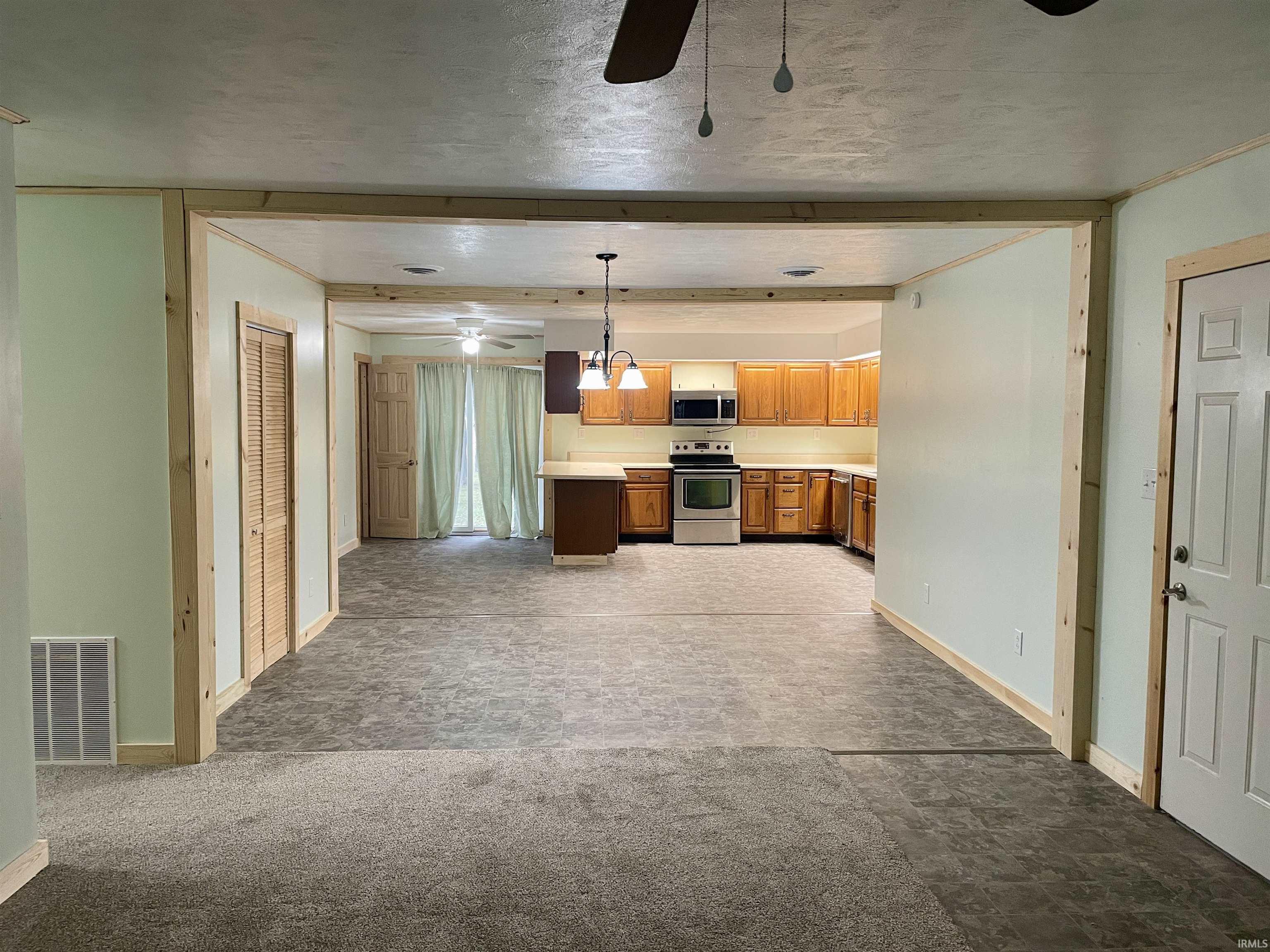 Kitchen with light countertops, open floor plan, a ceiling fan, appliances with stainless steel finishes, and decorative light fixtures