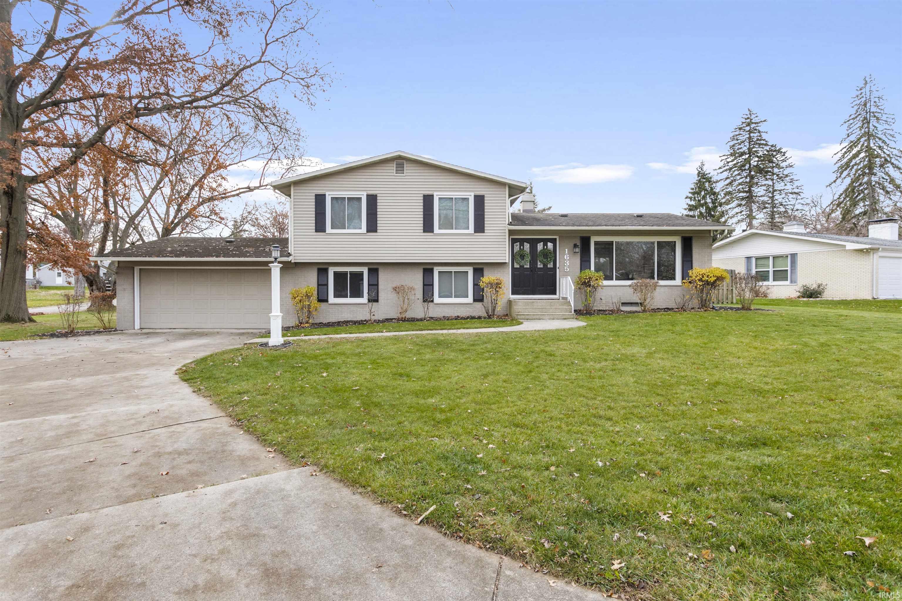 Tri-level home featuring a front yard, concrete driveway, and an attached garage