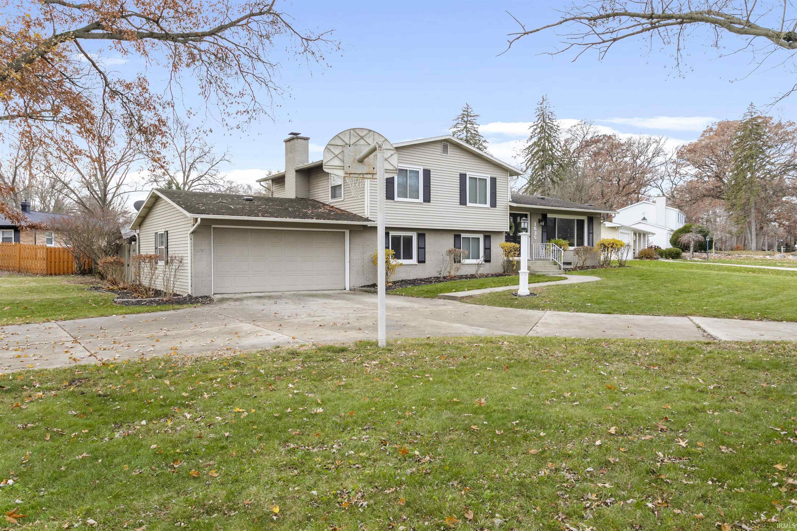 Tri-level home with driveway, a chimney, and an attached garage