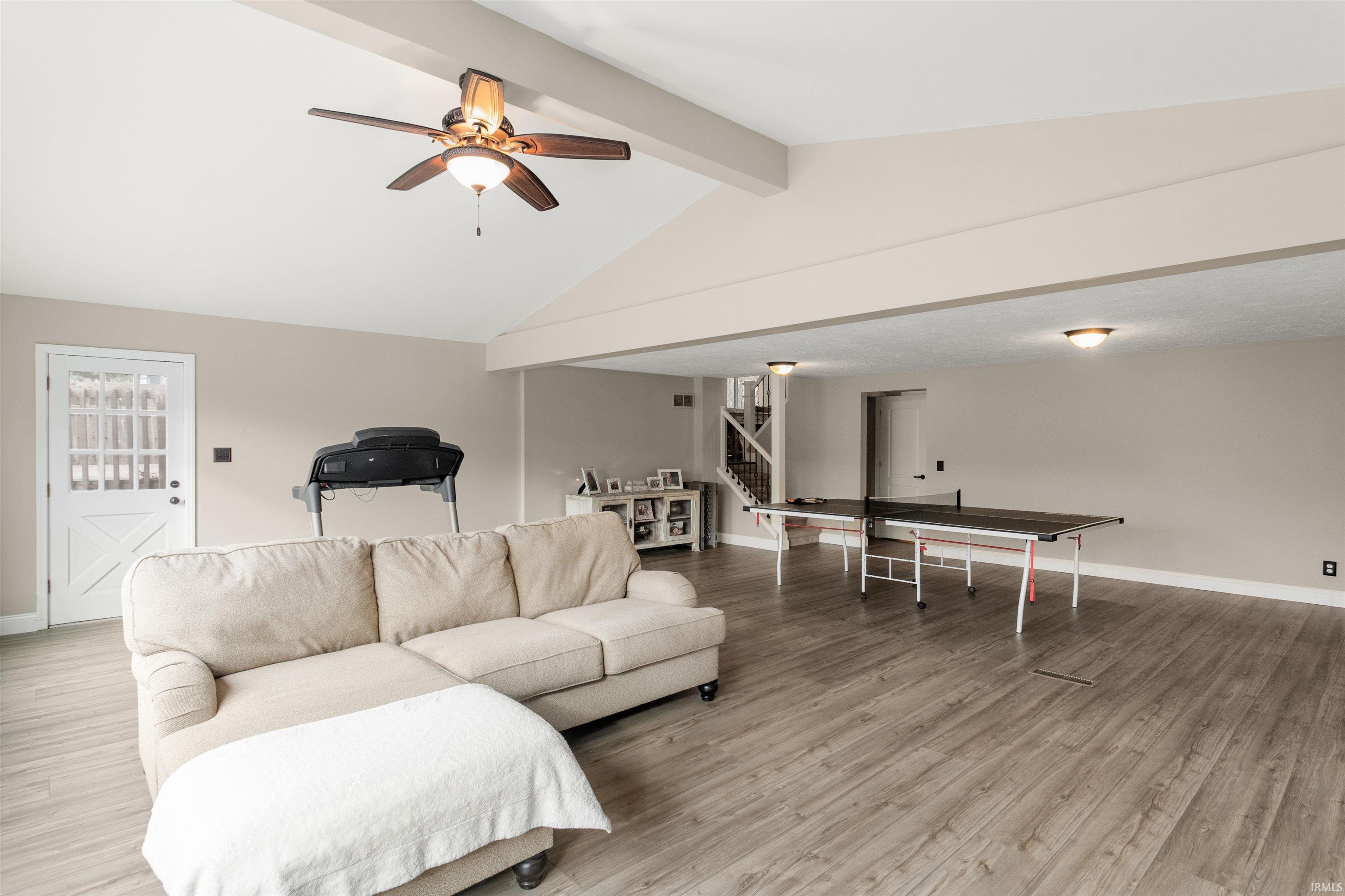 Living room featuring stairs, light wood-type flooring, and a ceiling fan