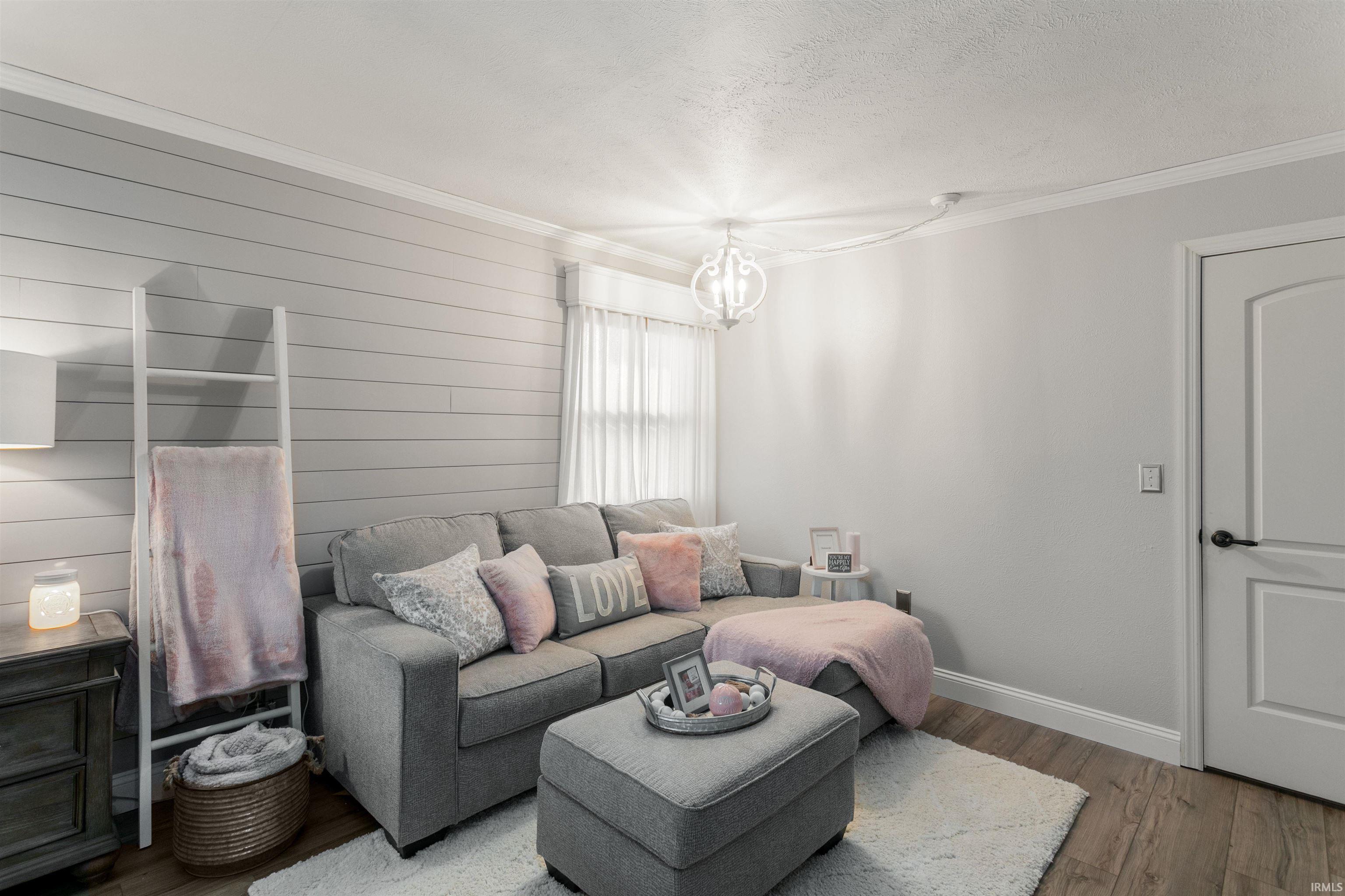 Living room featuring wood finished floors, ornamental molding, and a chandelier