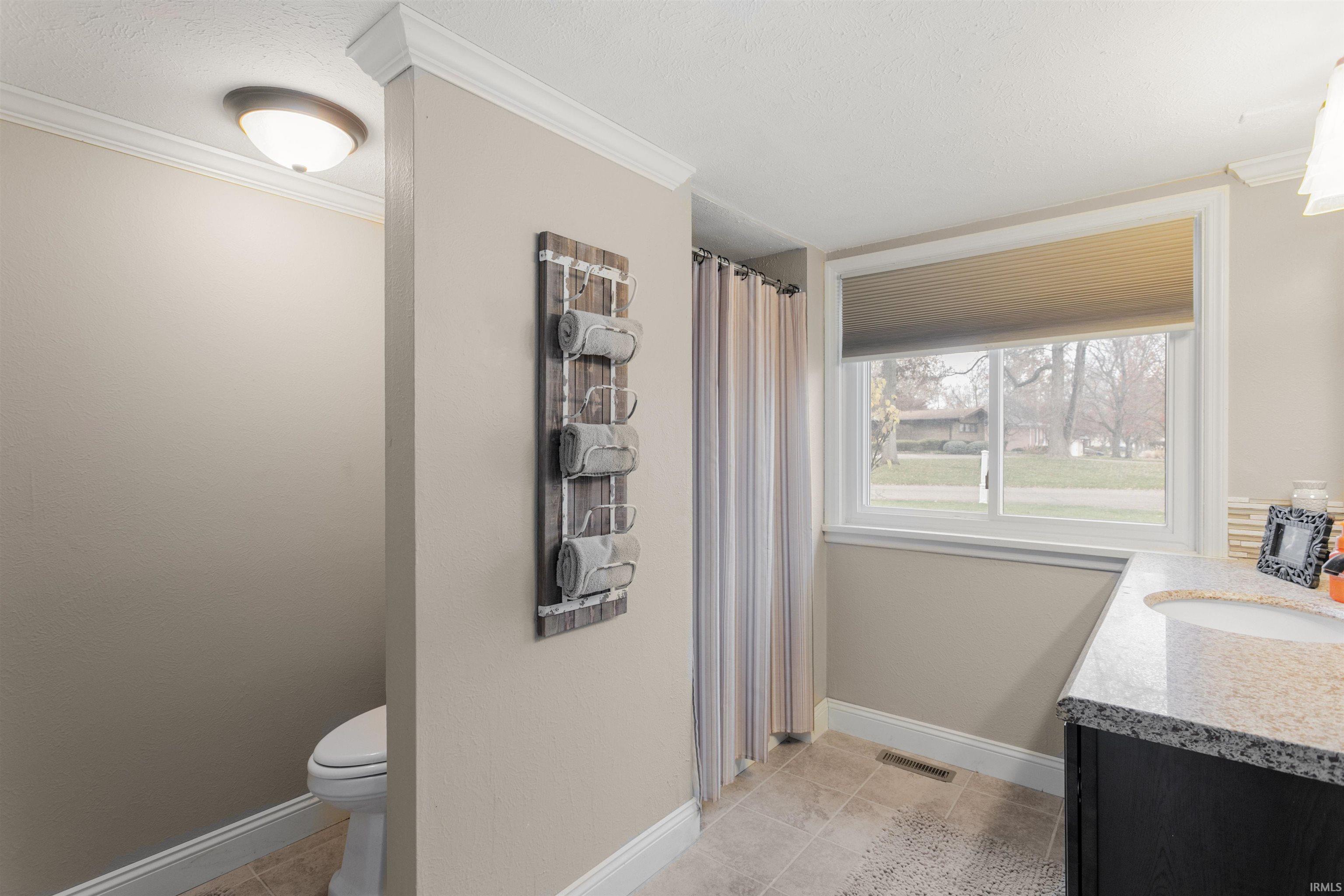 Bathroom featuring vanity, a shower with curtain, ornamental molding, and light tile patterned floors