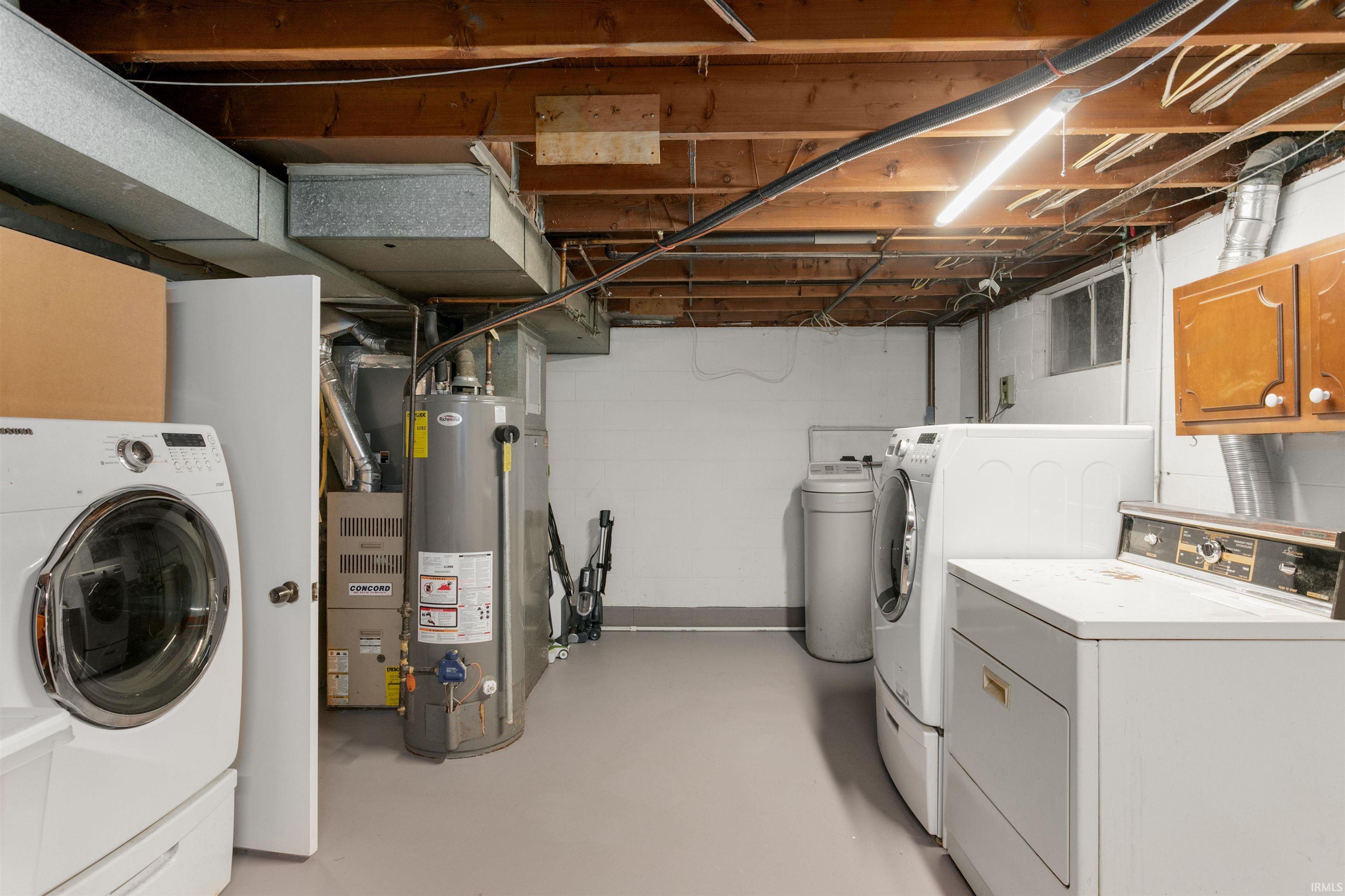 Laundry area with washer and dryer, water heater, and finished concrete flooring