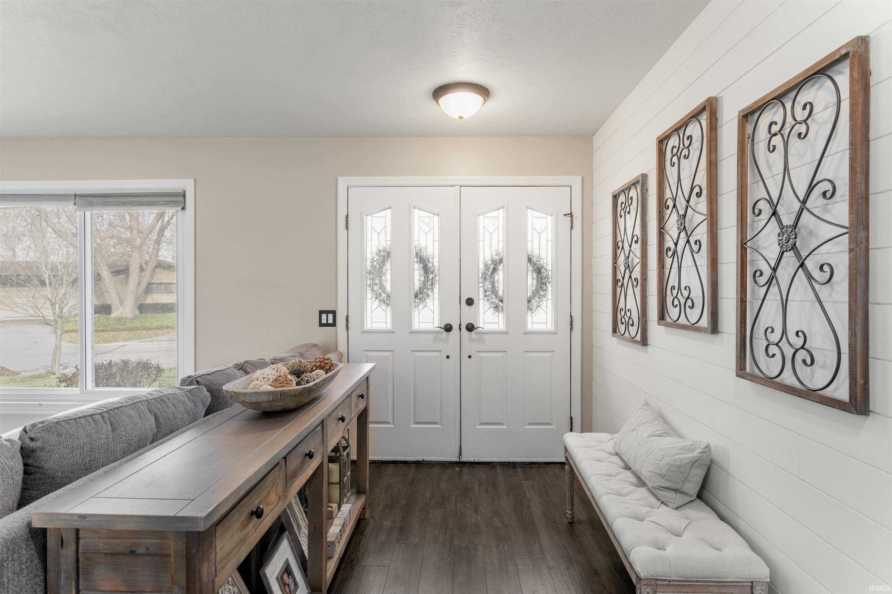 Entryway with dark wood finished floors and wooden walls