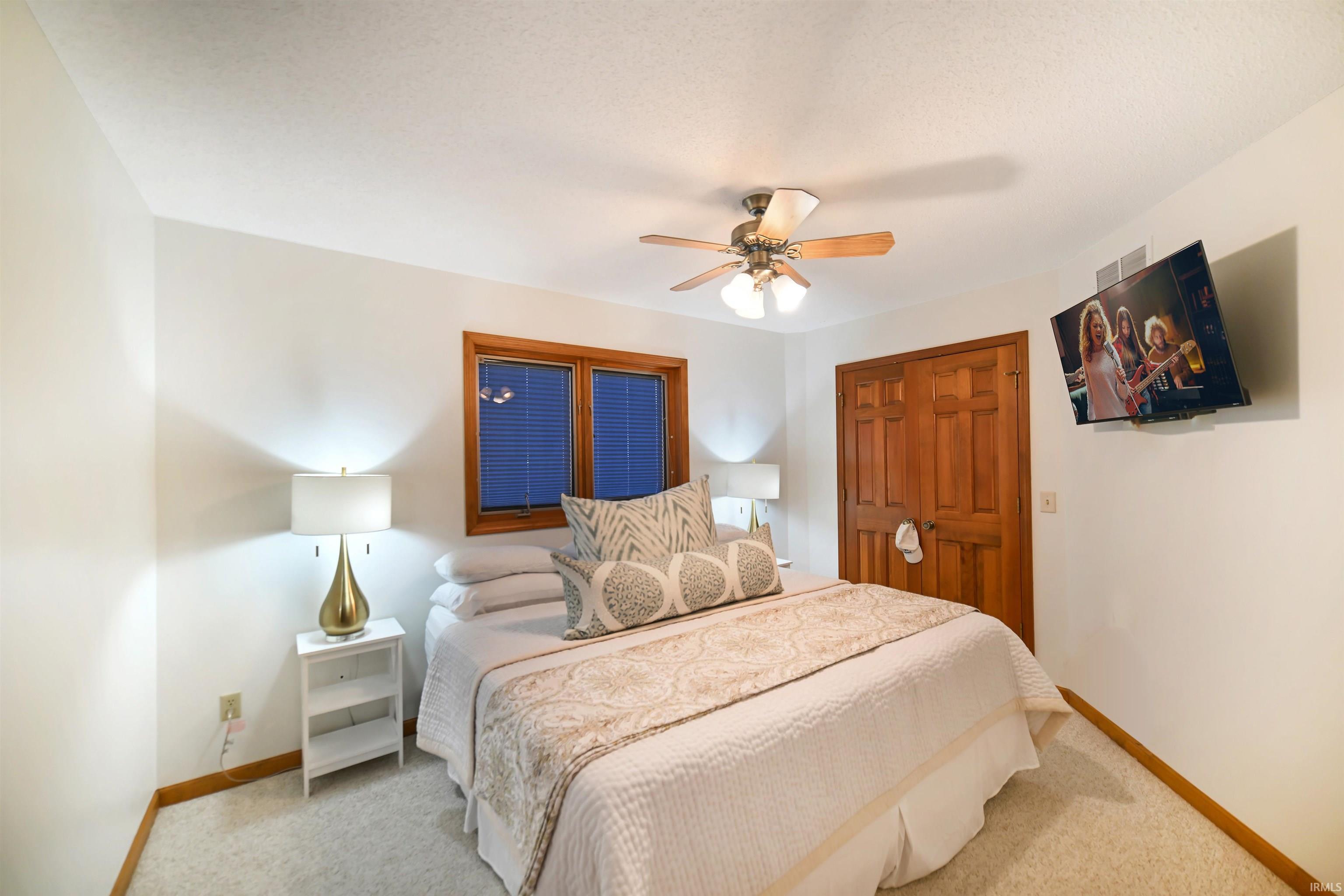 Carpeted bedroom with a ceiling fan and a closet