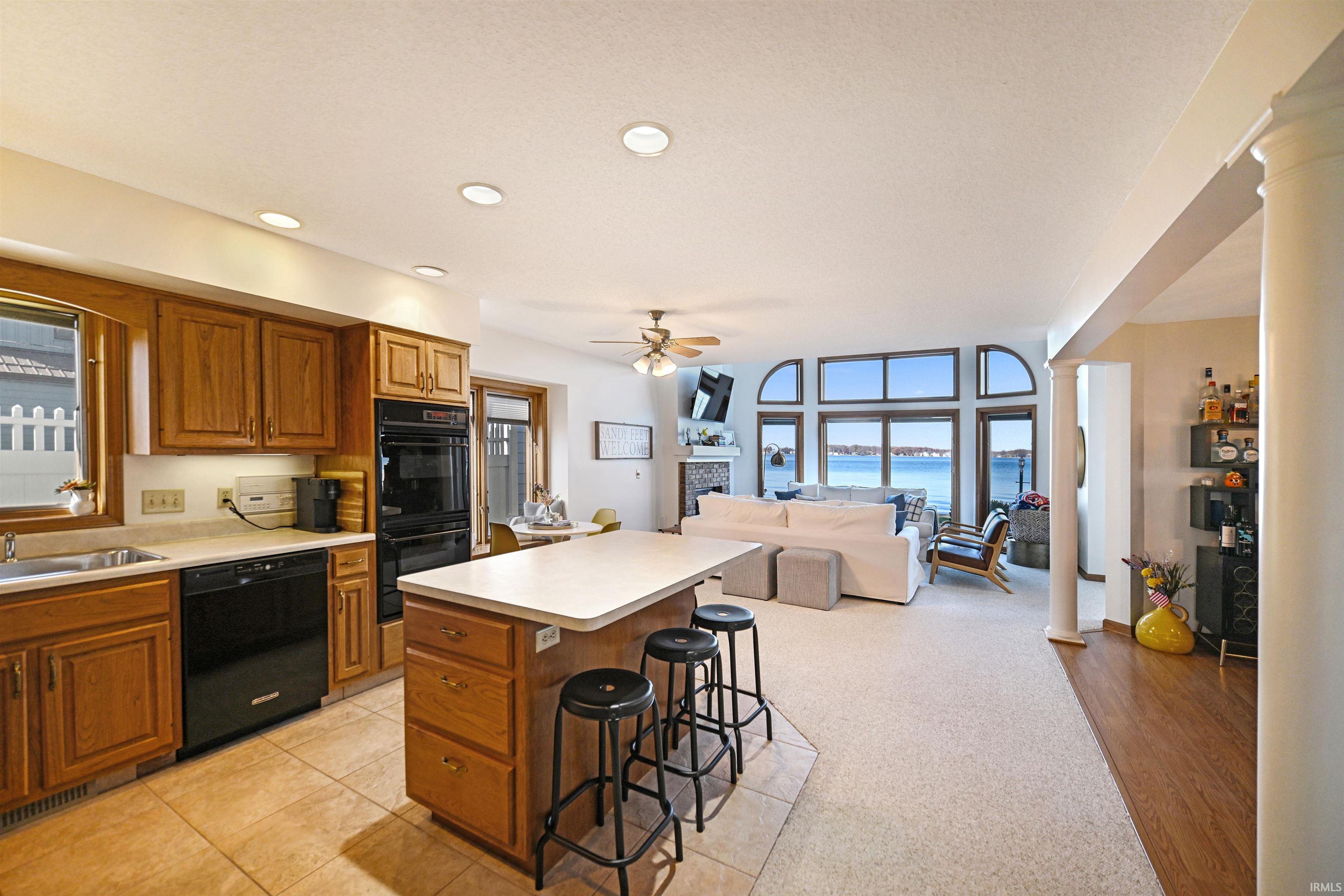 Kitchen featuring brown cabinets, a kitchen breakfast bar, light countertops, black appliances, and recessed lighting