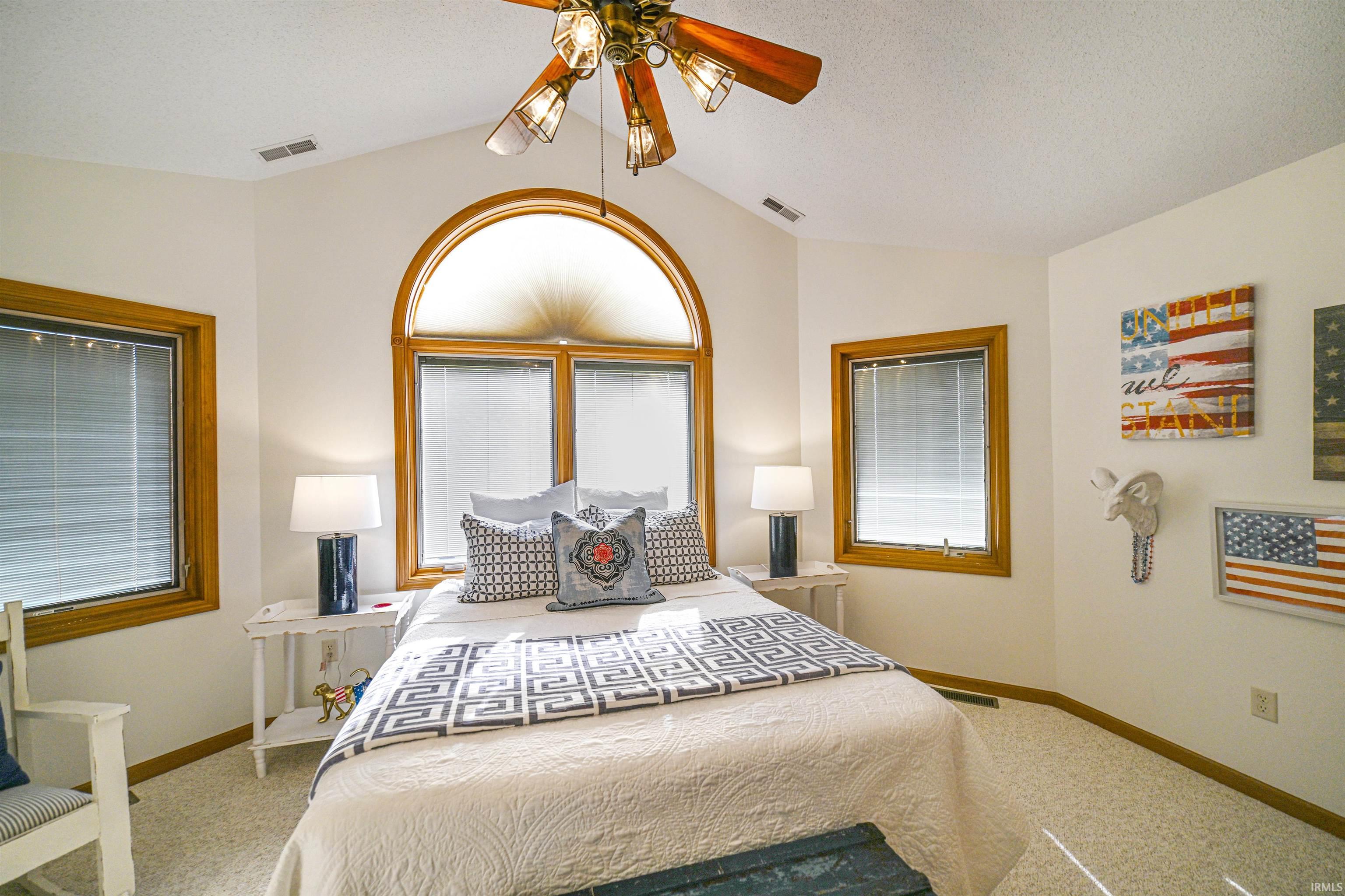 Bedroom featuring lofted ceiling, ceiling fan, carpet floors, and a textured ceiling