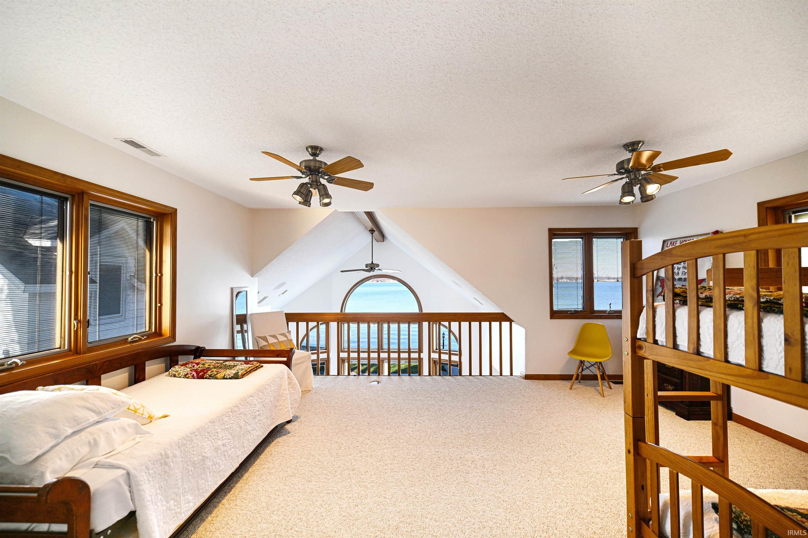 Carpeted bedroom featuring multiple windows, a textured ceiling, and ceiling fan