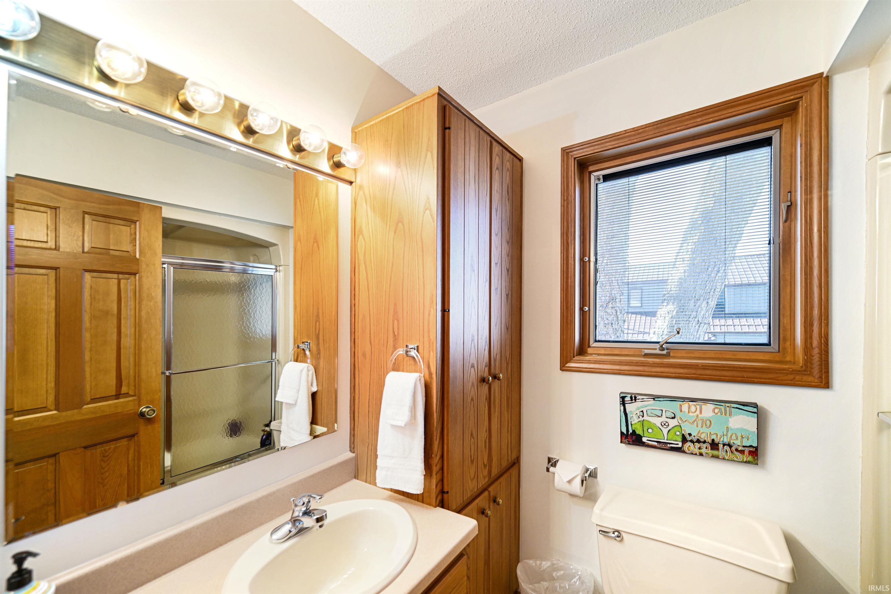 Bathroom featuring vanity, a textured ceiling, and enclosed tub / shower combo