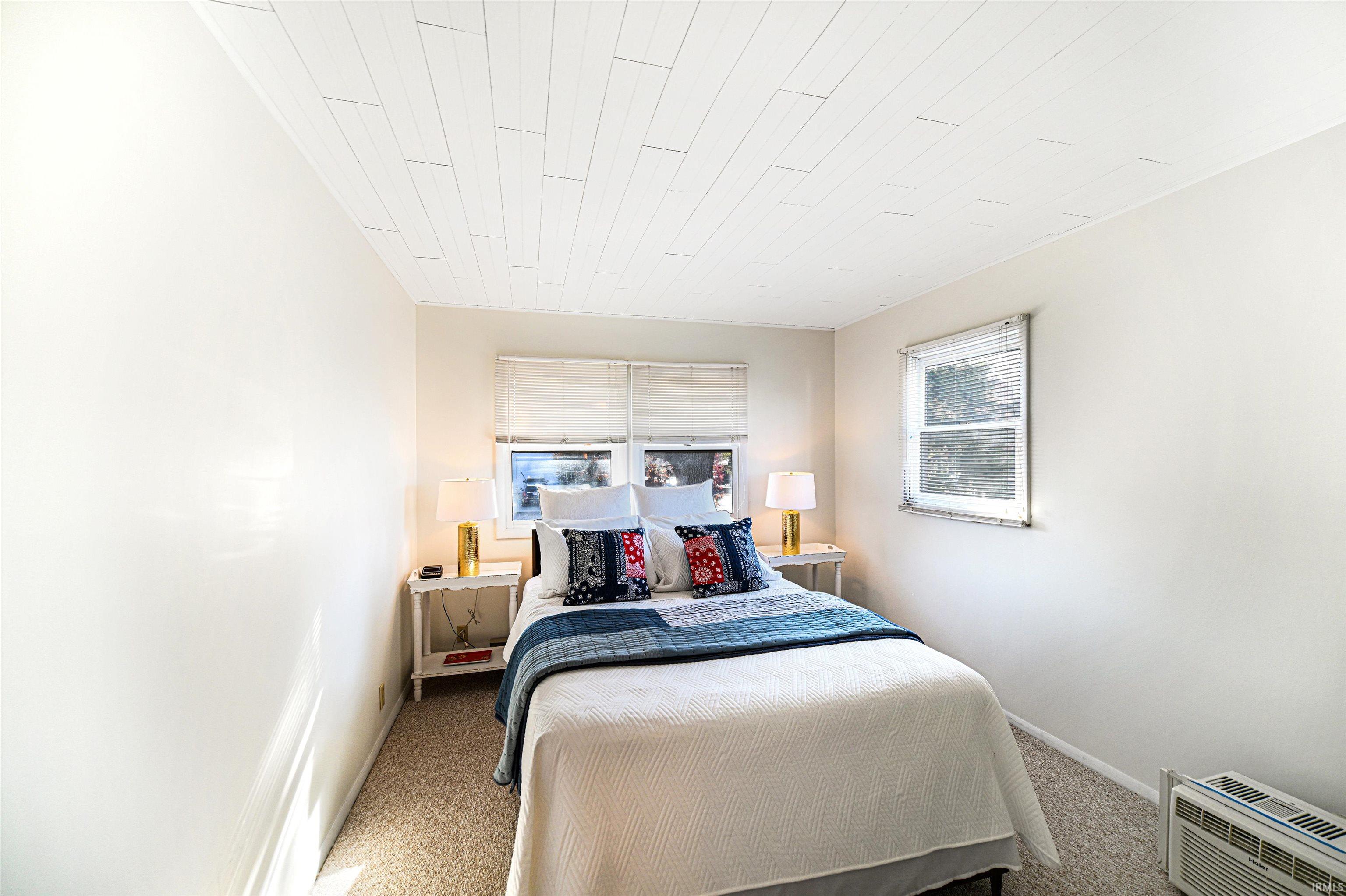 Carpeted bedroom with a wall unit AC and baseboards
