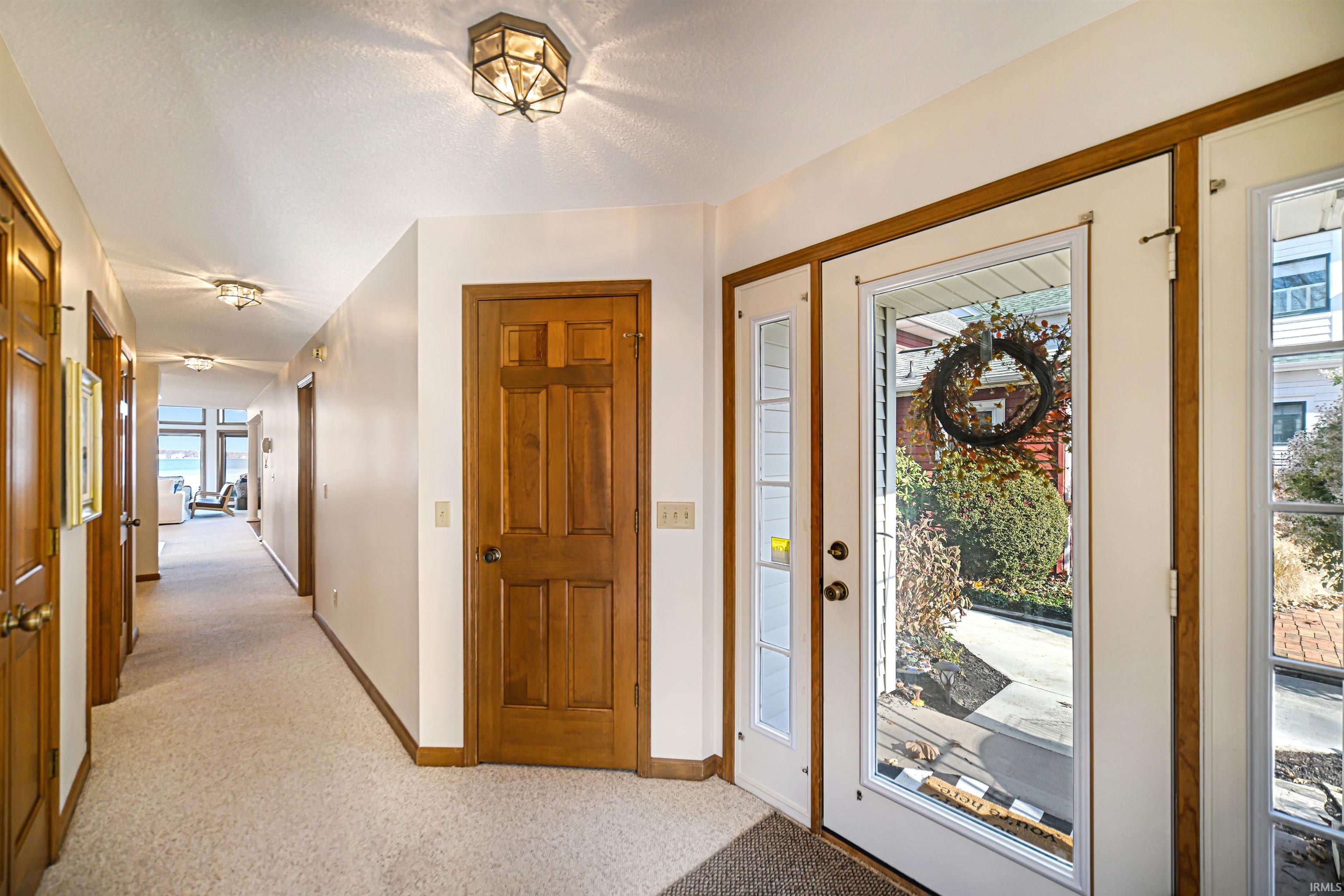 Foyer entrance featuring light colored carpet and baseboards