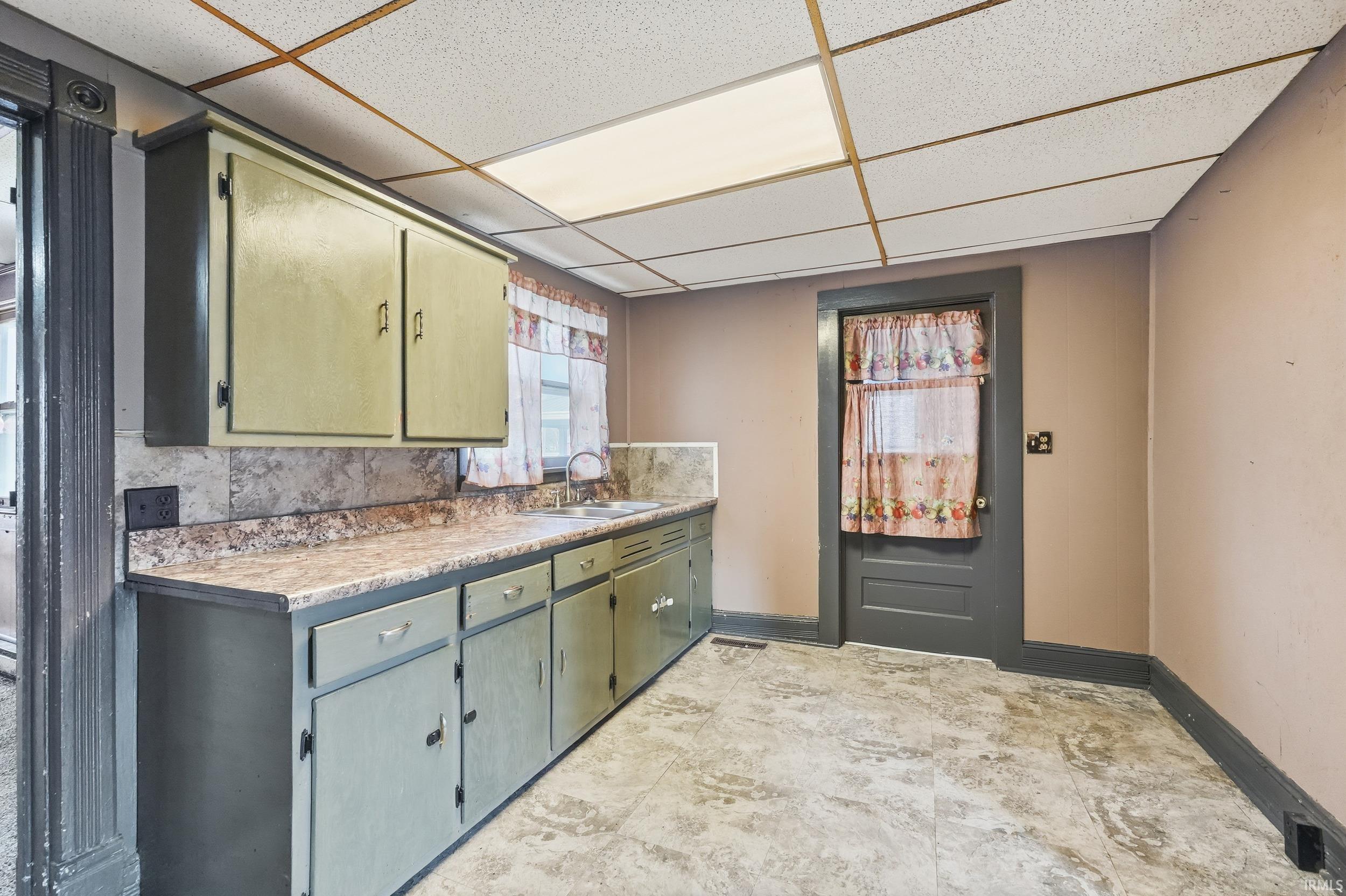 Kitchen with light countertops and a drop ceiling