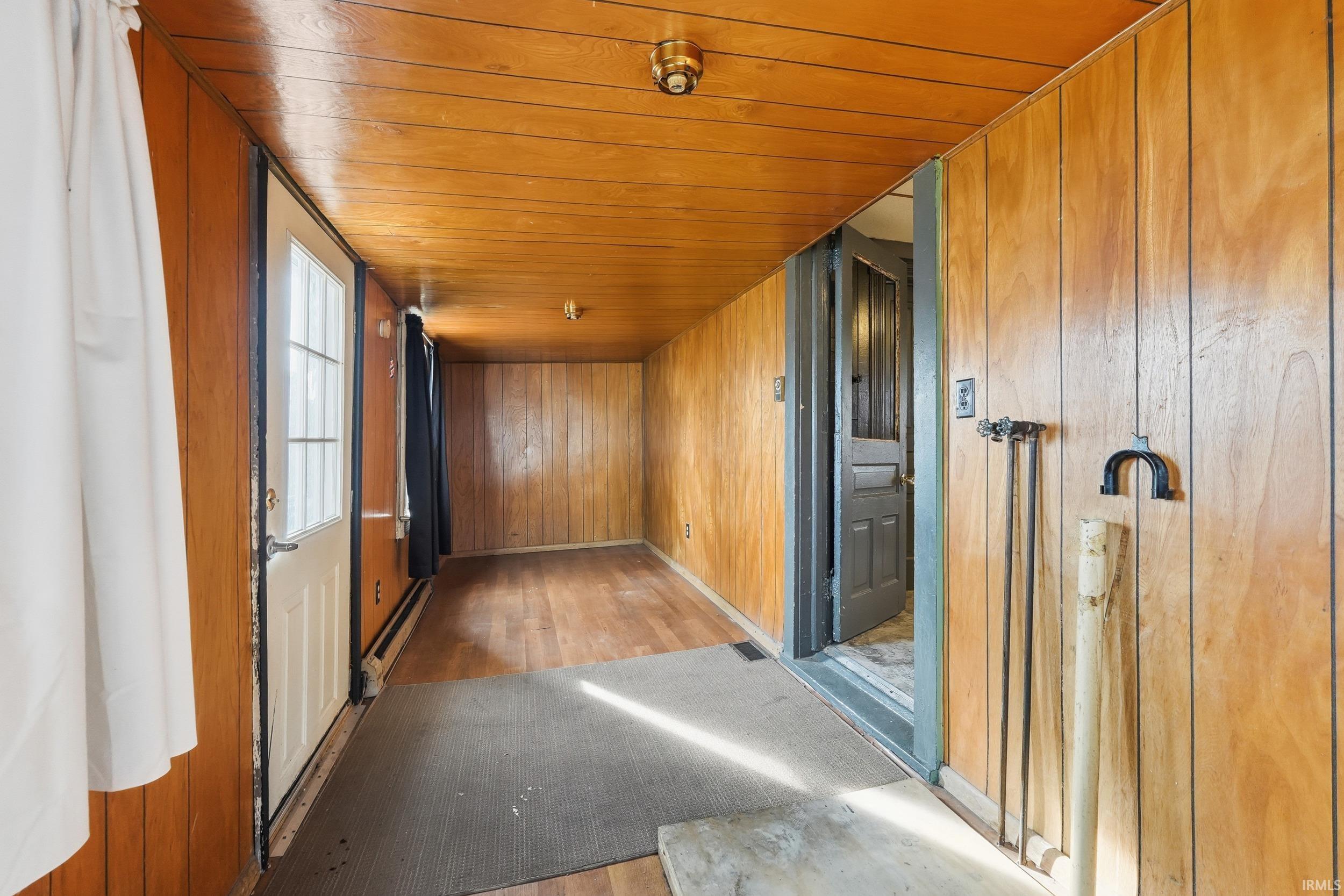 Hall with wood ceiling, hardwood / wood-style floors, baseboard heating, and wood walls