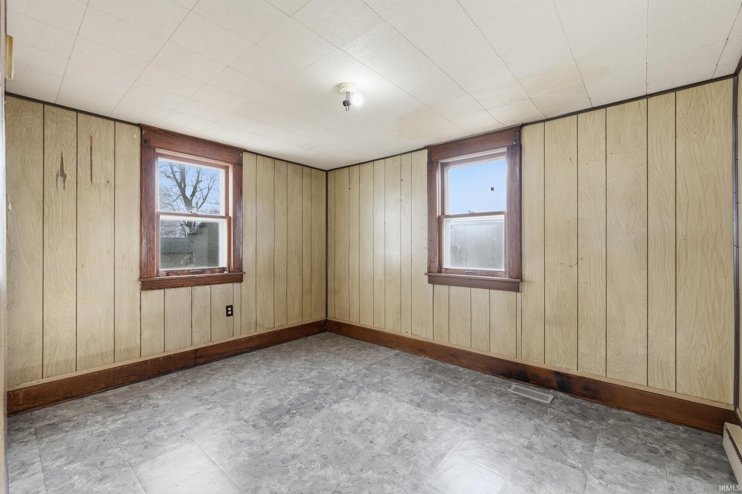 Unfurnished room featuring wooden walls, tile patterned floors, and a baseboard radiator