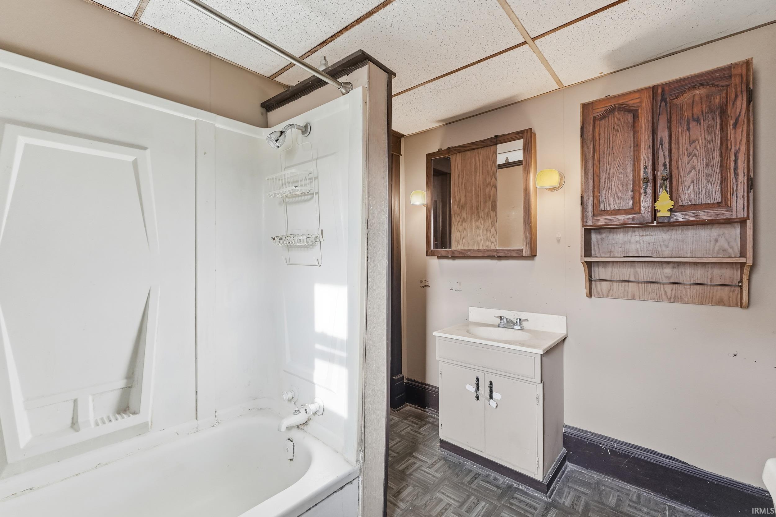 Full bathroom with vanity, bathing tub / shower combination, and a drop ceiling