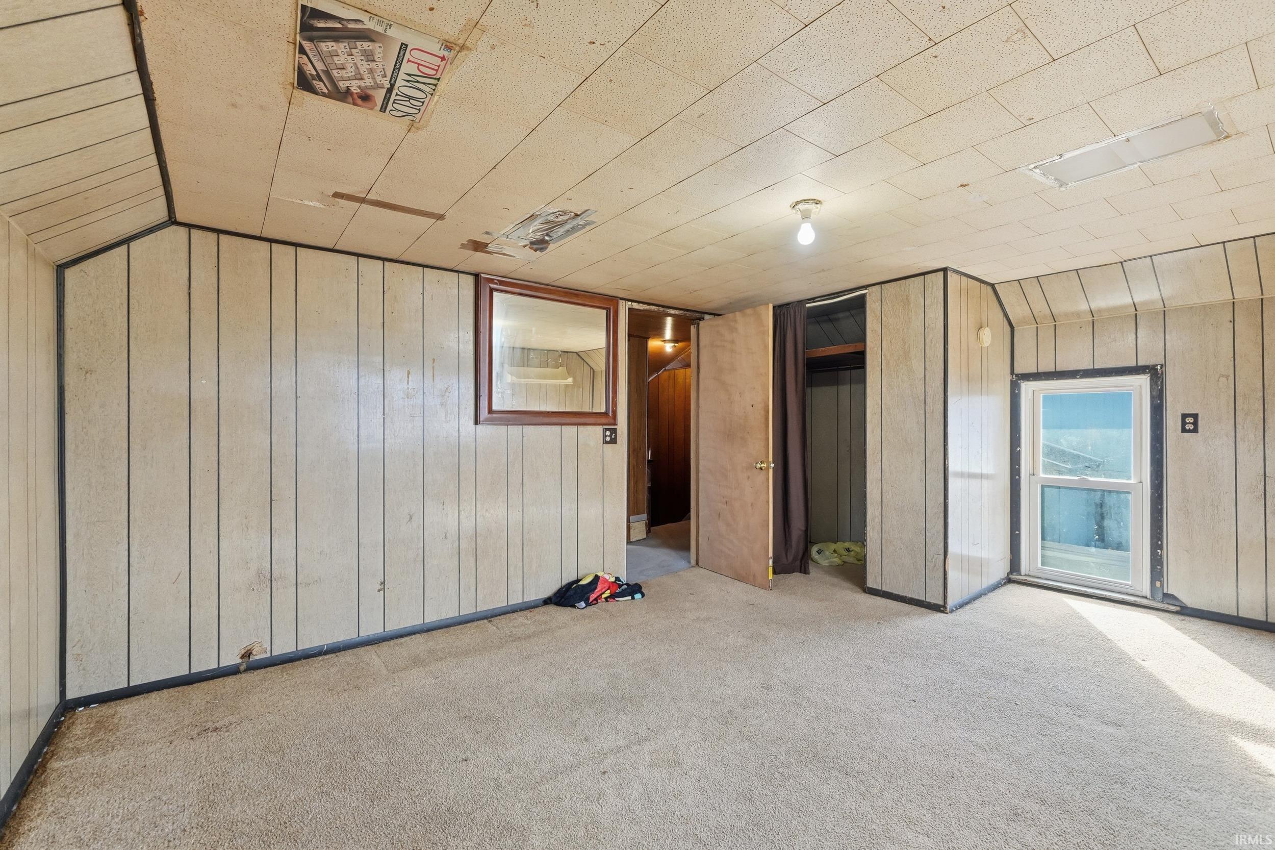 Unfurnished bedroom with wood walls, a closet, and carpet flooring