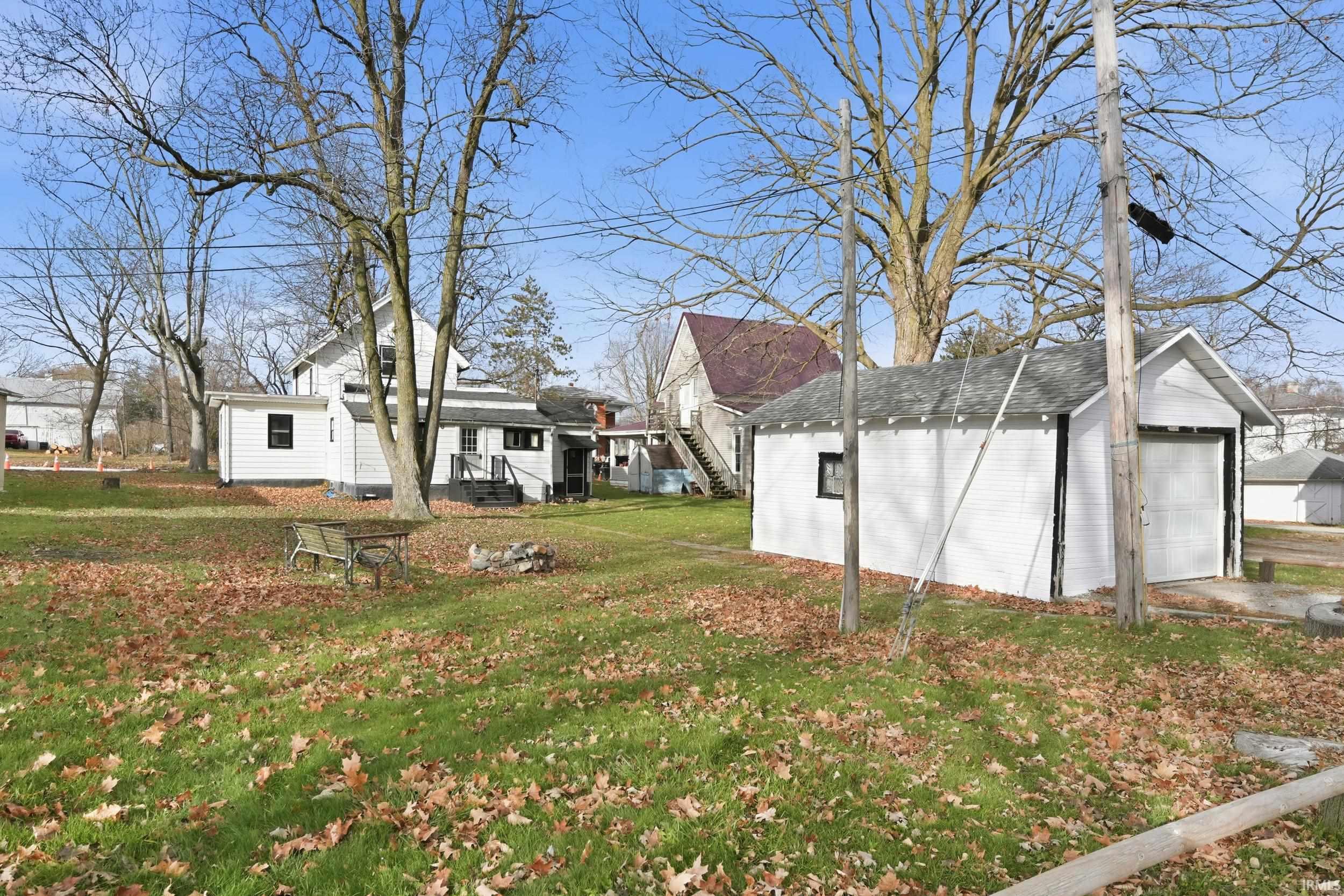 View of grassy yard with an outdoor structure, a detached garage, and stairway
