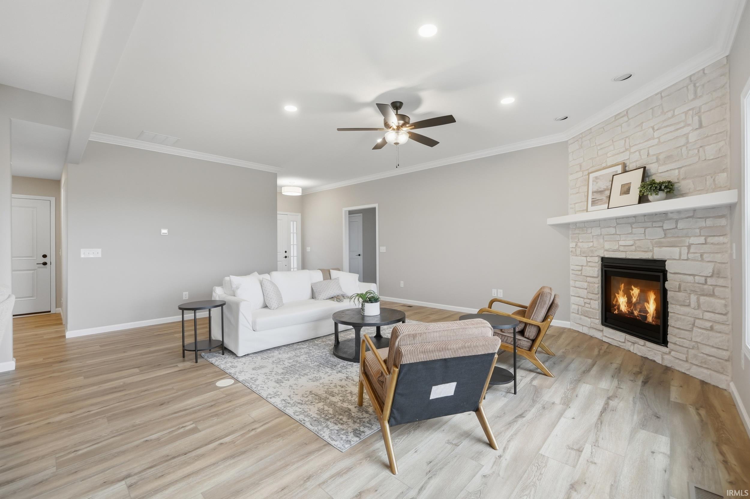 Living room with a ceiling fan, light wood-style flooring, a fireplace, recessed lighting, and crown molding