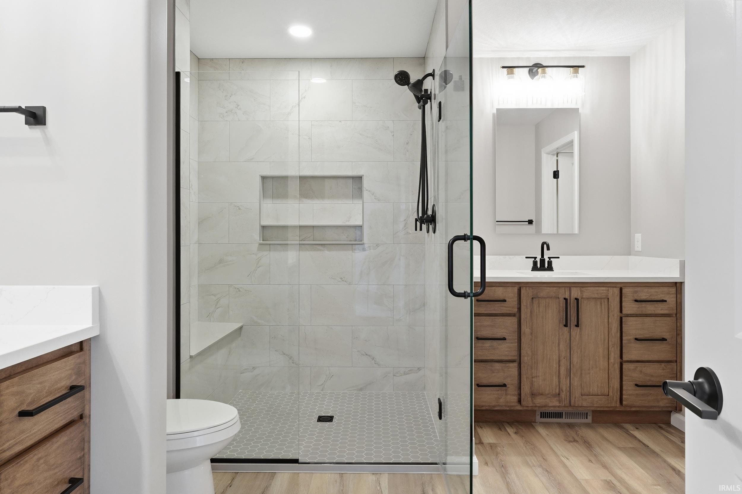 Full bathroom with vanity, a stall shower, light wood-style flooring, and recessed lighting