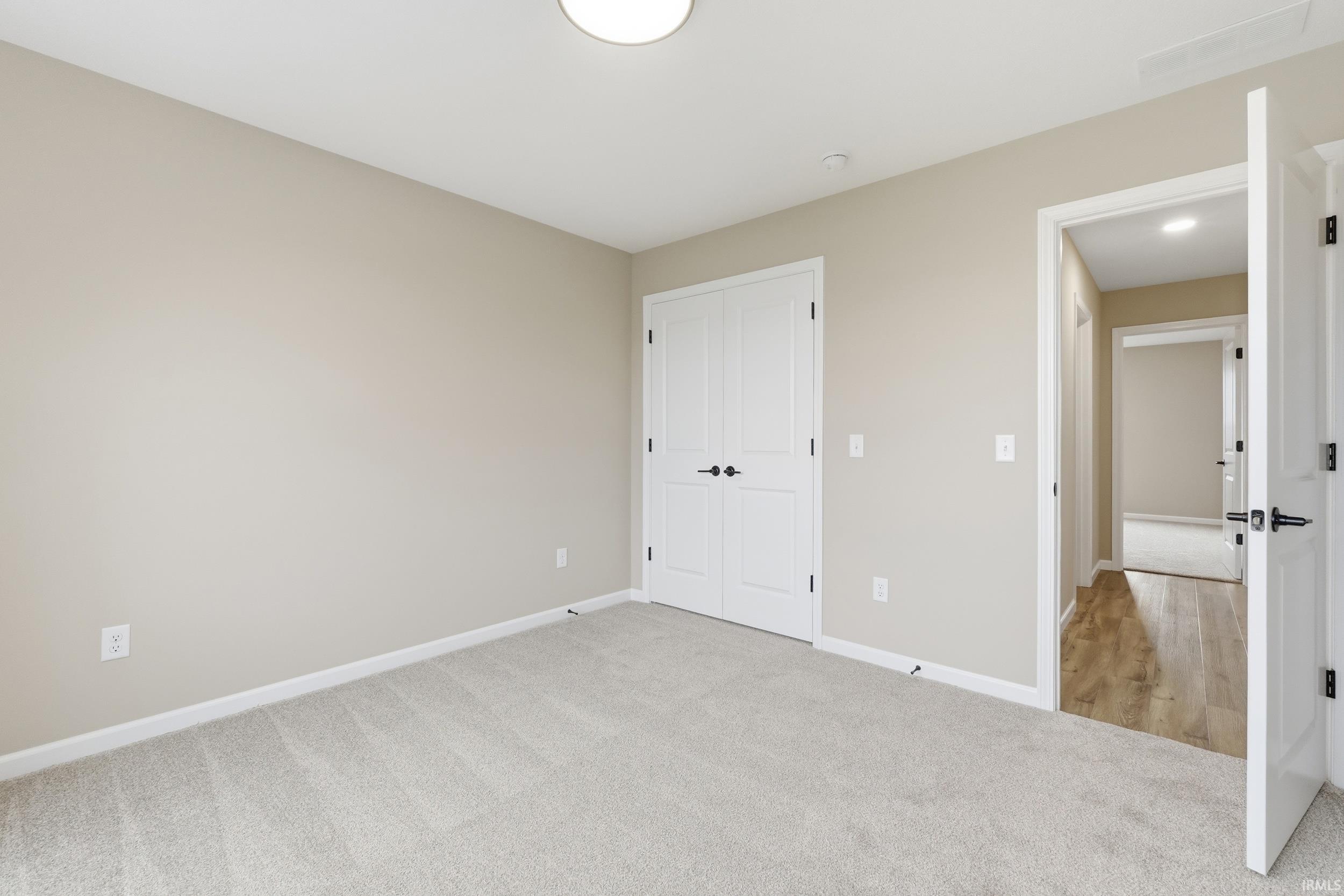 Unfurnished bedroom with light colored carpet and a closet