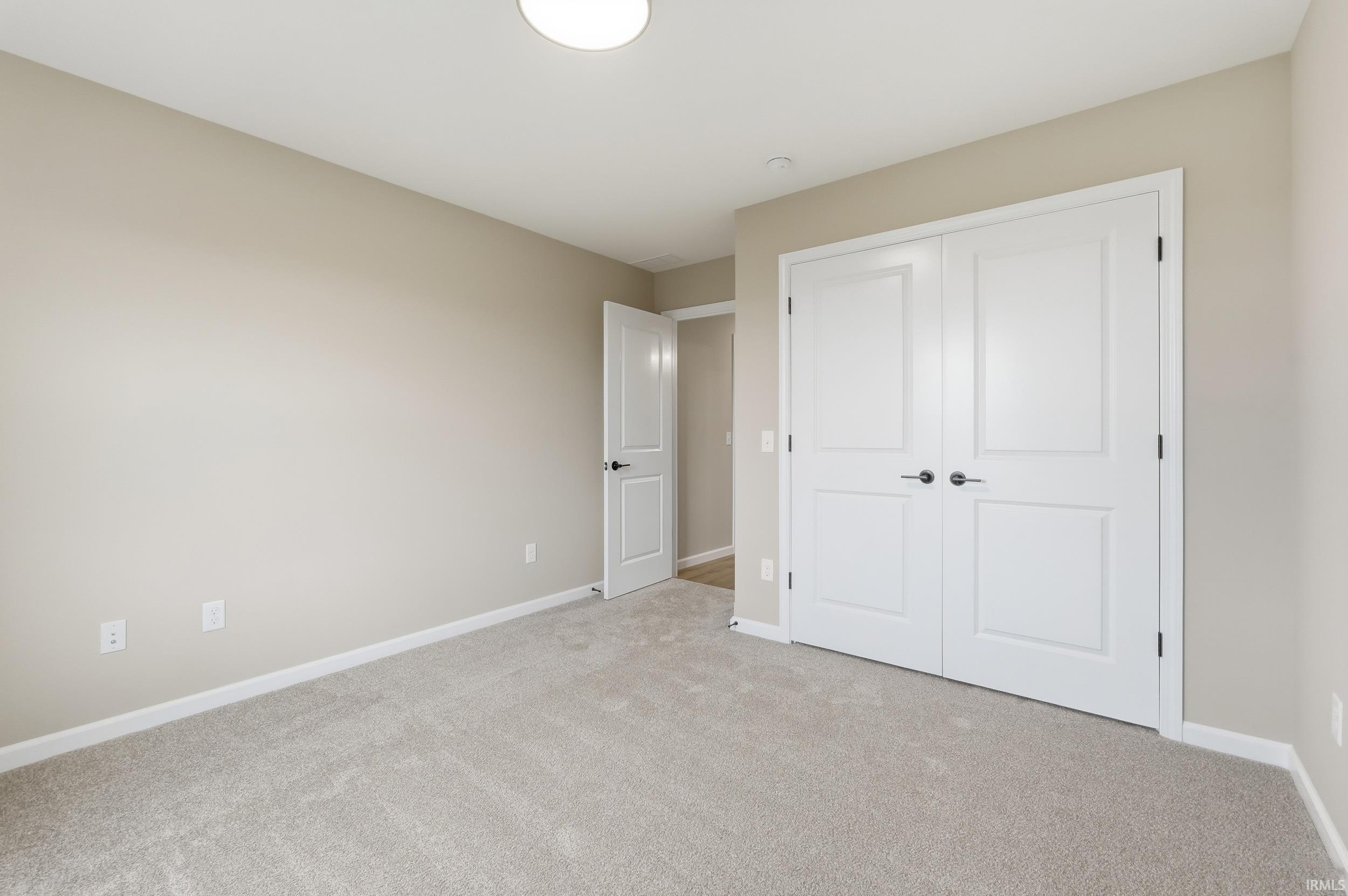 Unfurnished bedroom with light colored carpet and a closet
