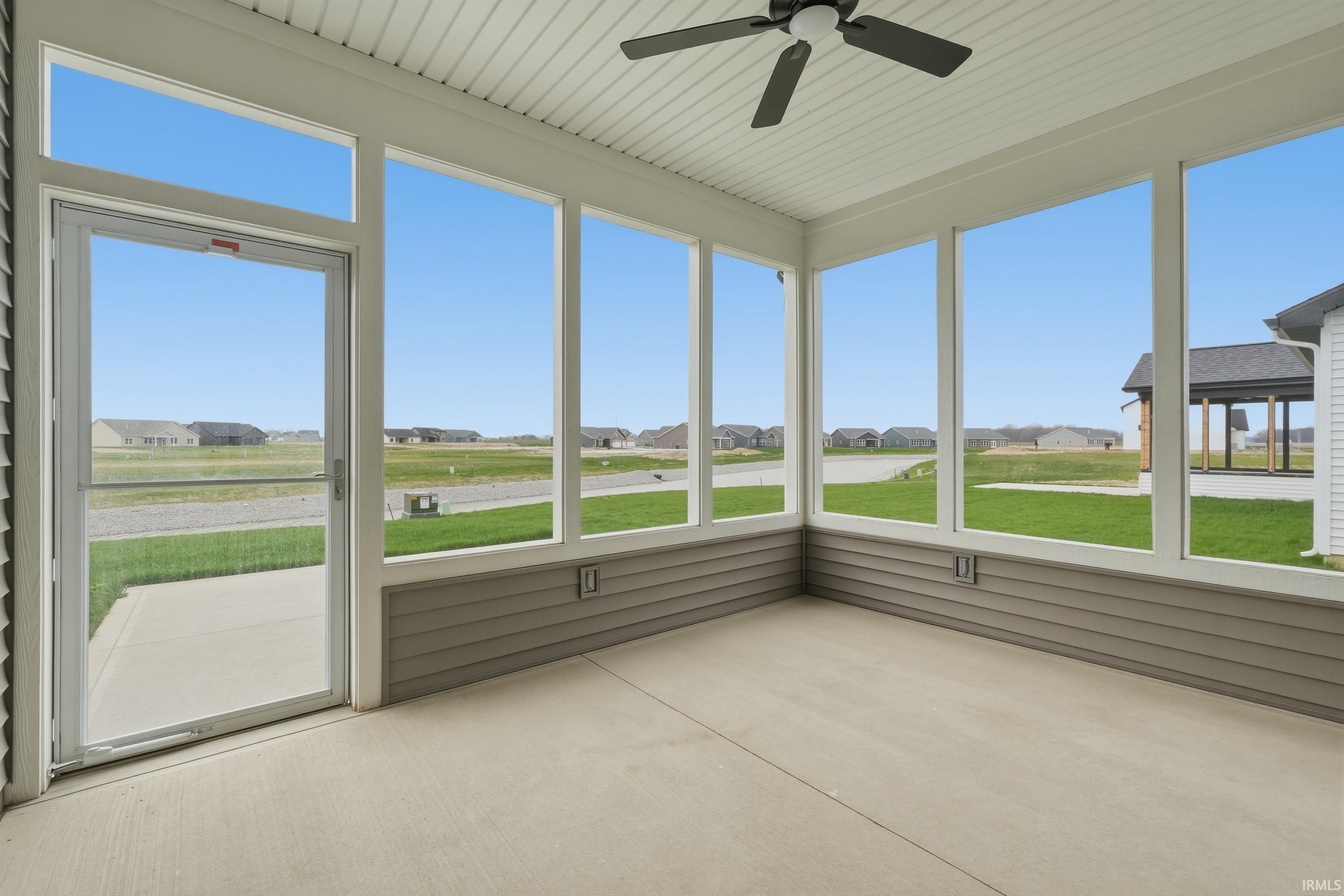 Unfurnished sunroom featuring ceiling fan and a residential view