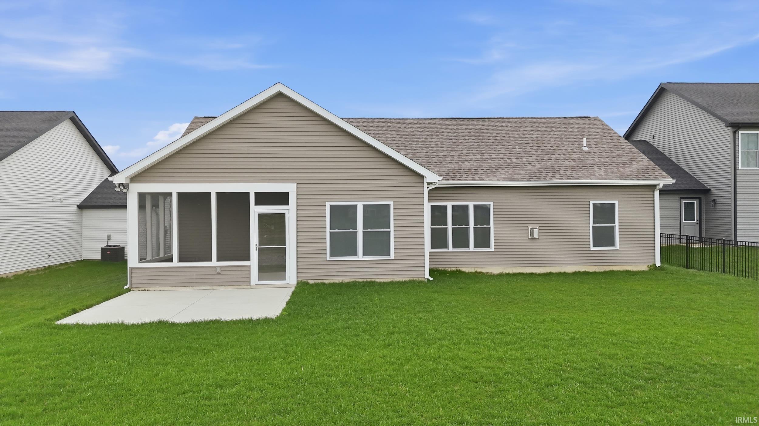 Rear view of property featuring a sunroom, roof with shingles, and a patio area