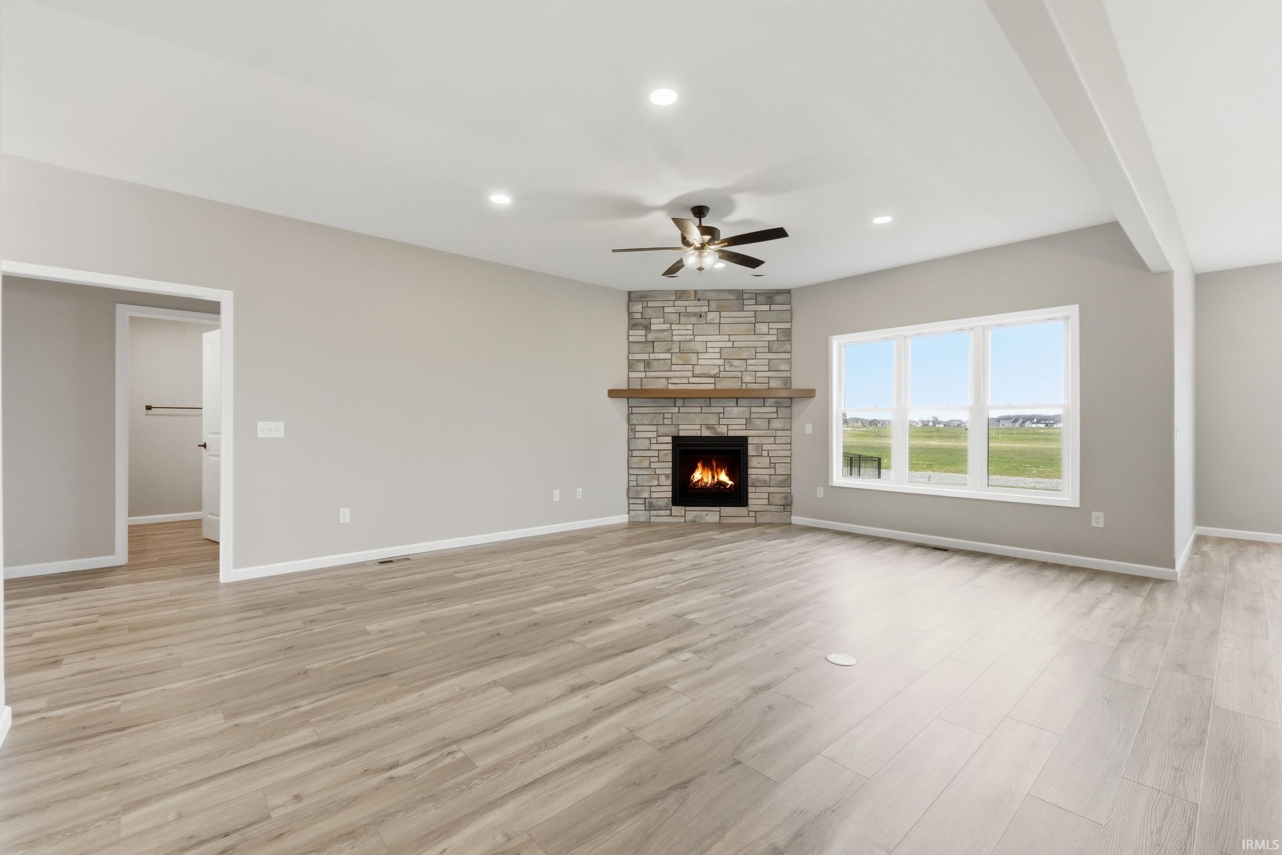 Unfurnished living room featuring a ceiling fan, recessed lighting, a stone fireplace, and light wood-type flooring