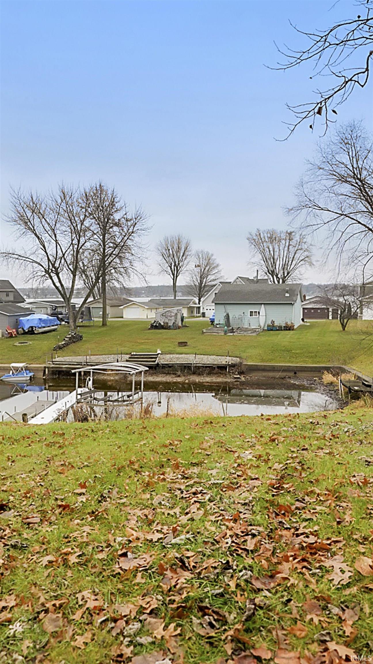 View of green lawn featuring a water view and a dock