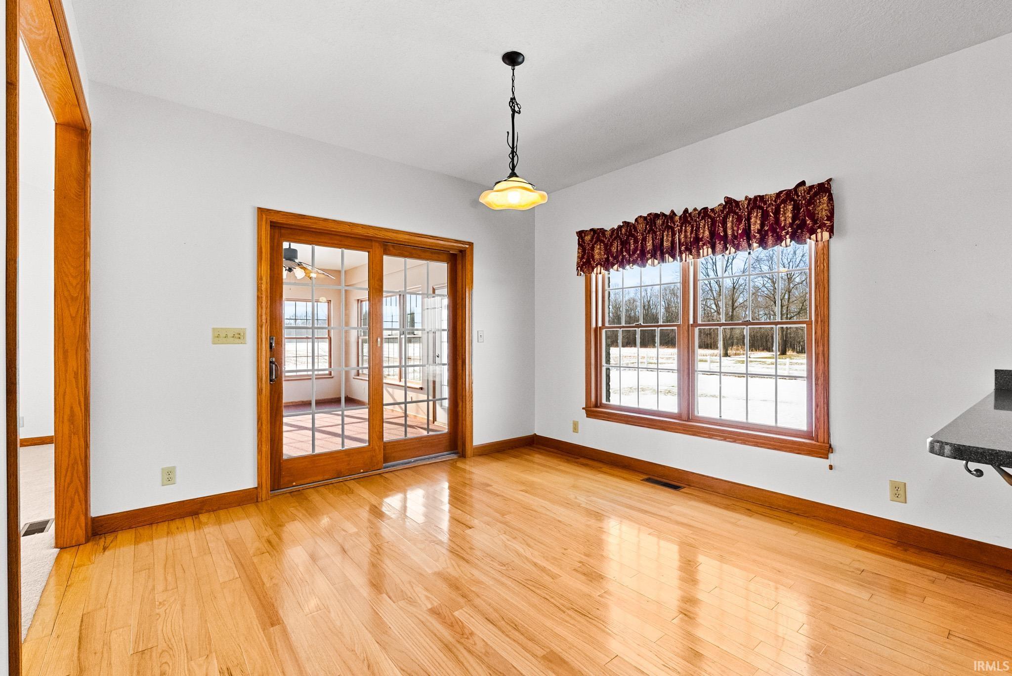 Unfurnished dining area featuring light wood-style flooring and baseboards